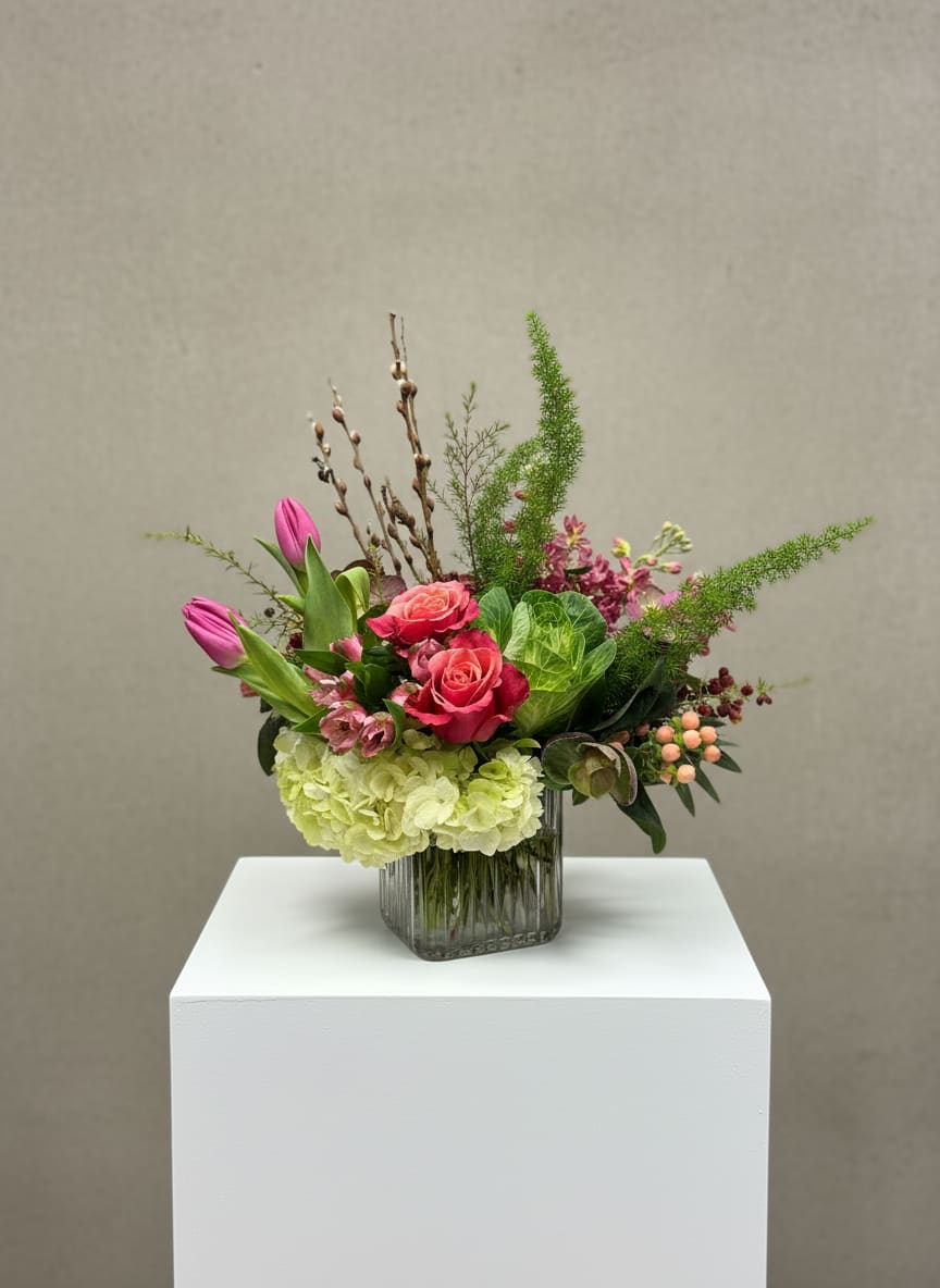 Pink roses and tulips in a glass vase with green hydrangea