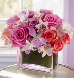 Pink and red roses with white orchids in a glass vase