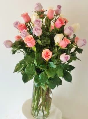Tall glass vase of mixed pink, lavender, peach, and white roses with long stems