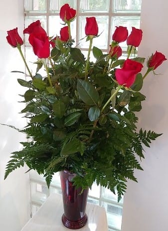 Tall bouquet of red roses in a burgundy vase