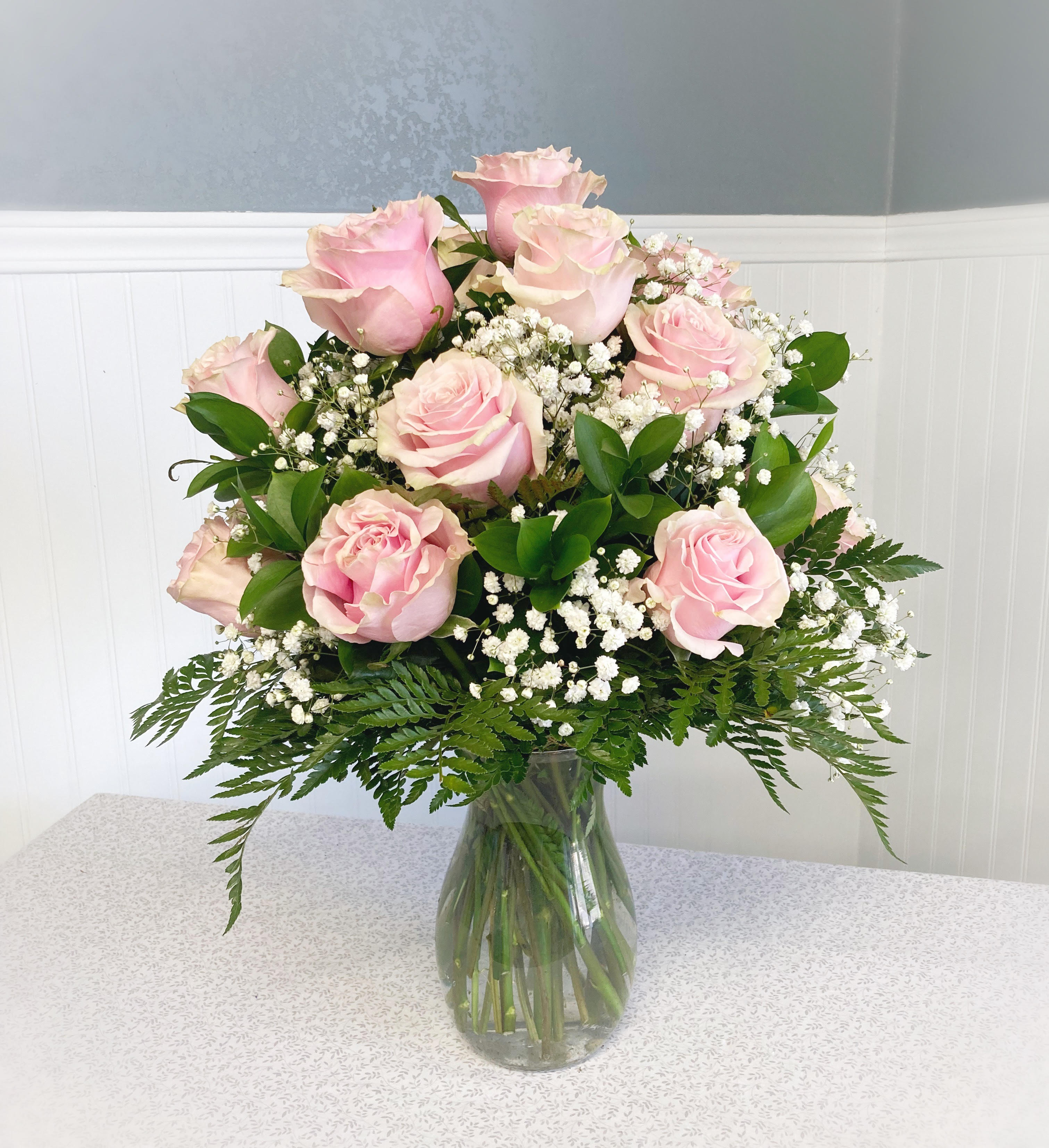 Pink roses arranged in a clear glass vase with white filler flowers