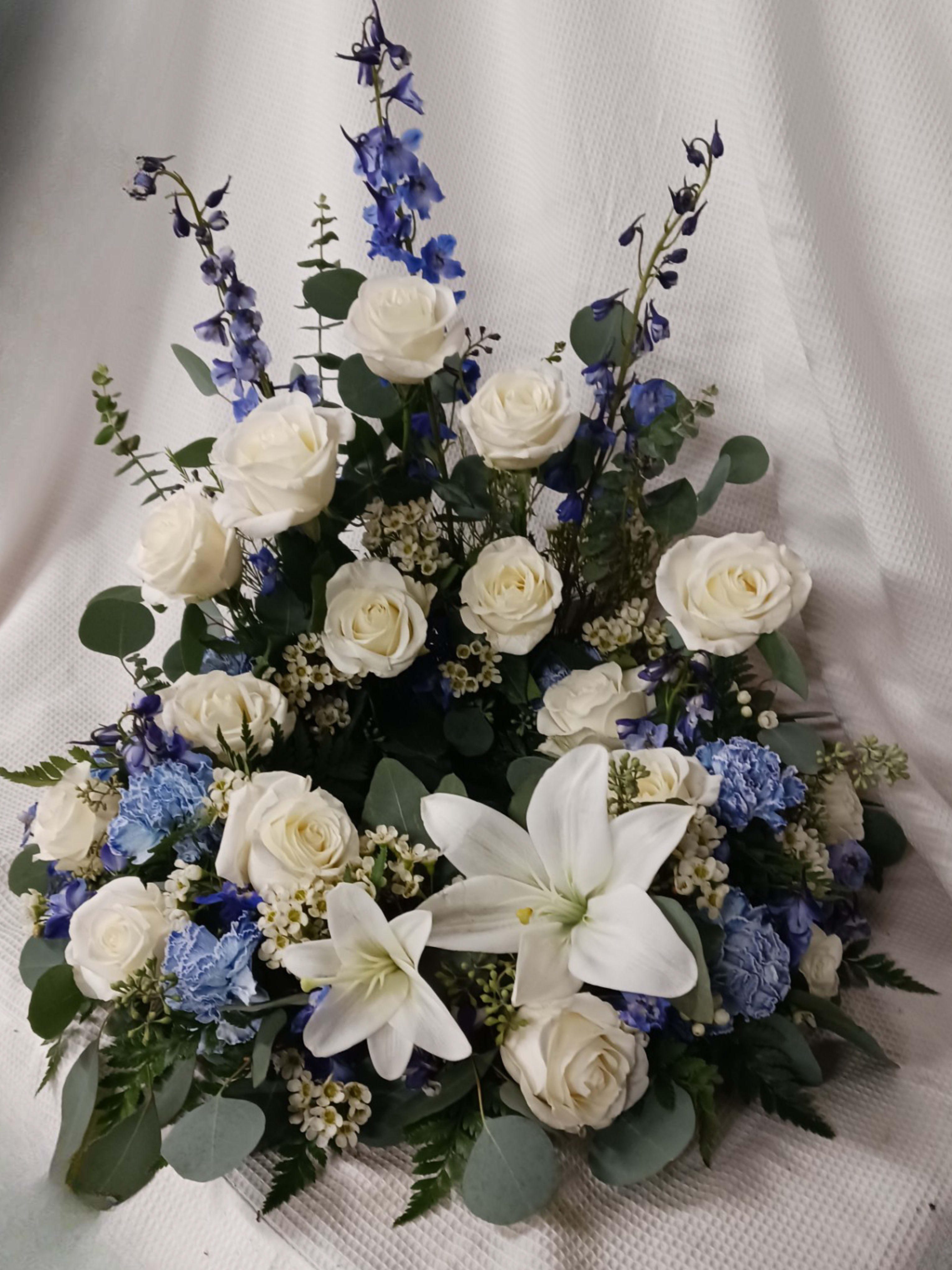 White roses and lilies with blue flowers in a low arrangement