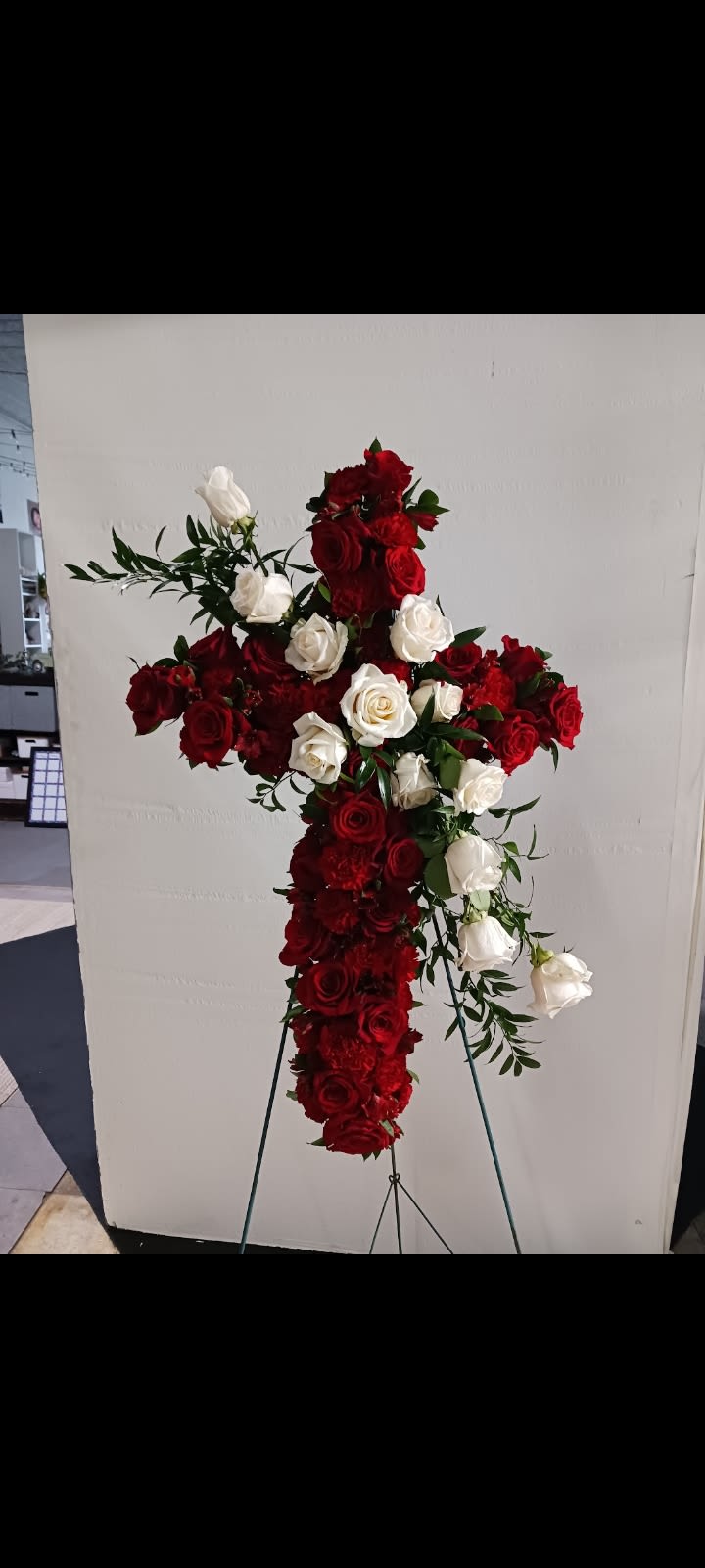 Cross-shaped floral arrangement of red and white roses on a stand