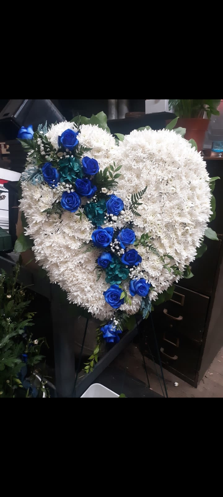 Heart-shaped white floral arrangement with blue roses