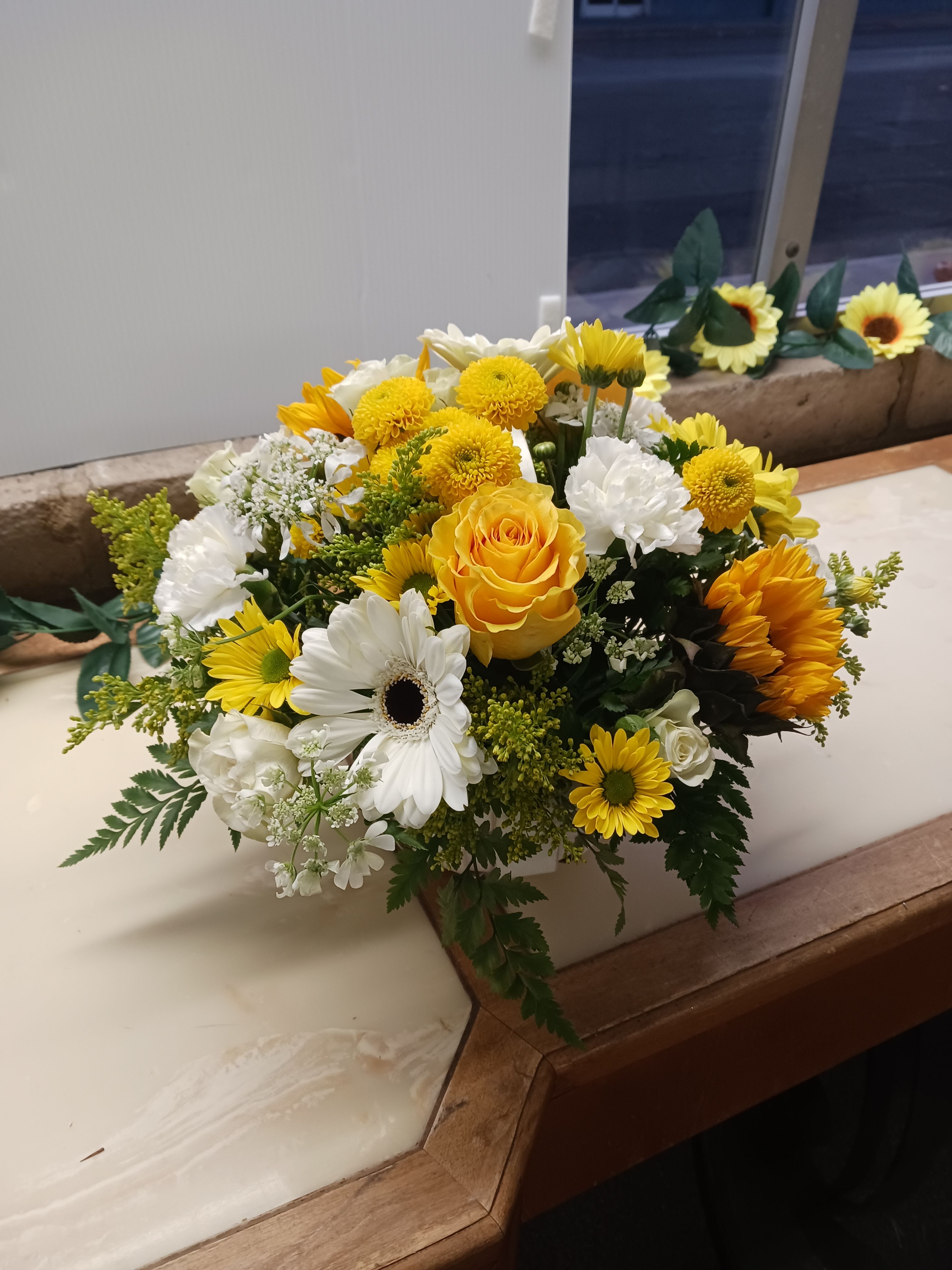 Yellow and white mixed flower arrangement in a white container