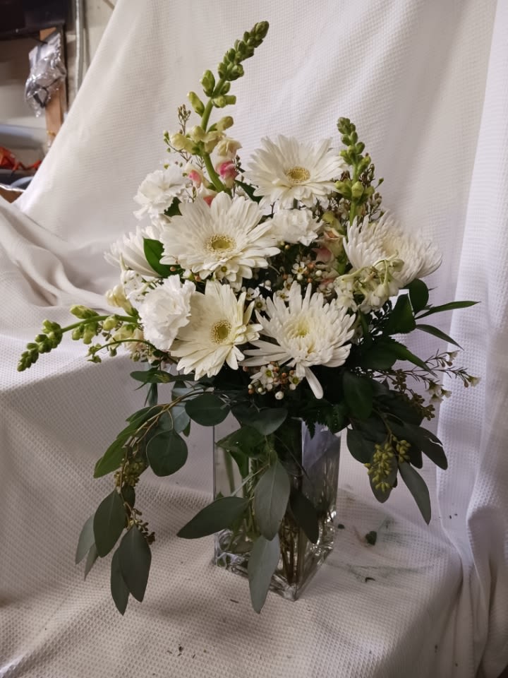 White gerbera daisies and snapdragons in a clear glass vase
