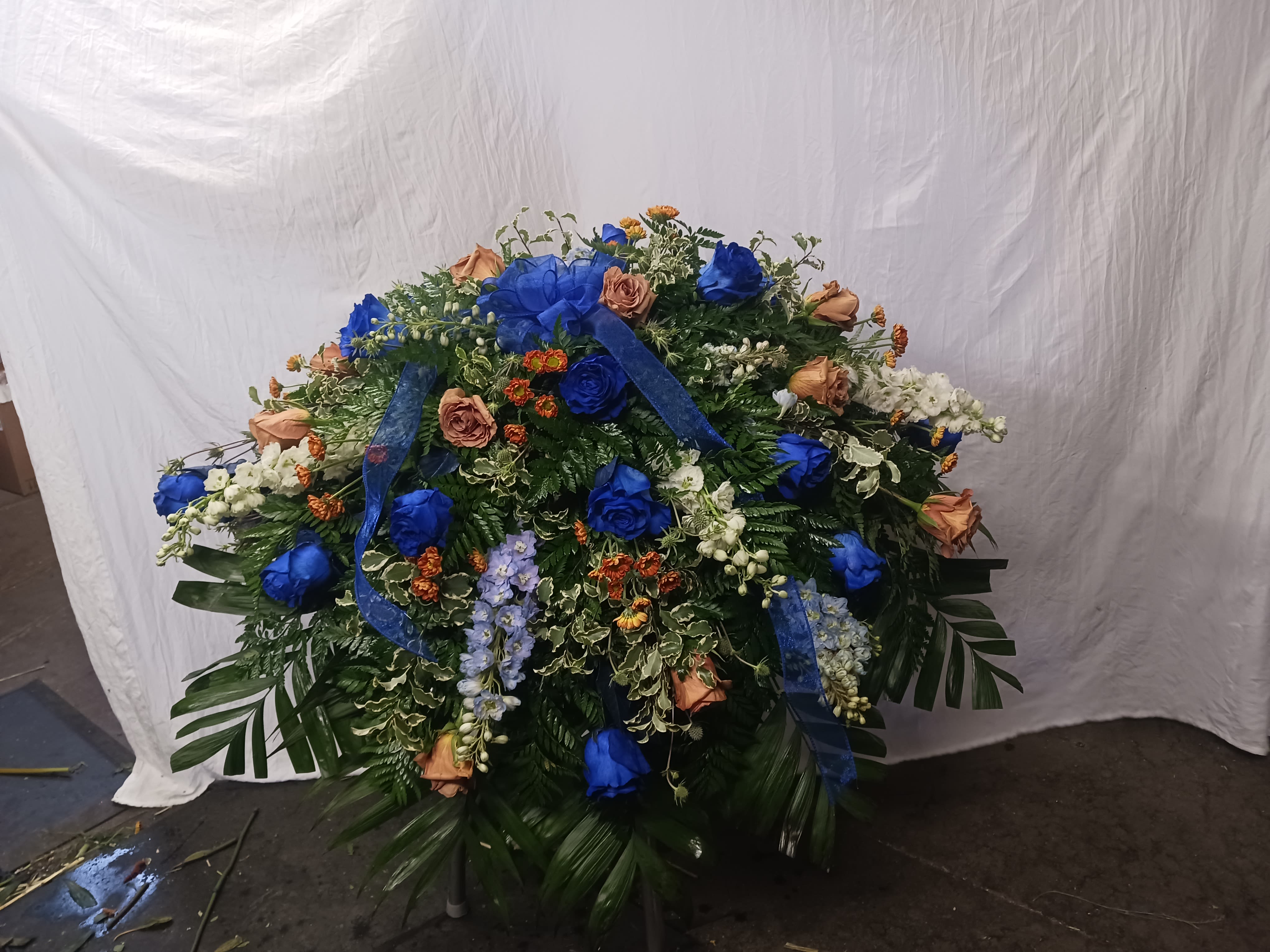 Large floral spray with blue and peach roses and ribbon accents