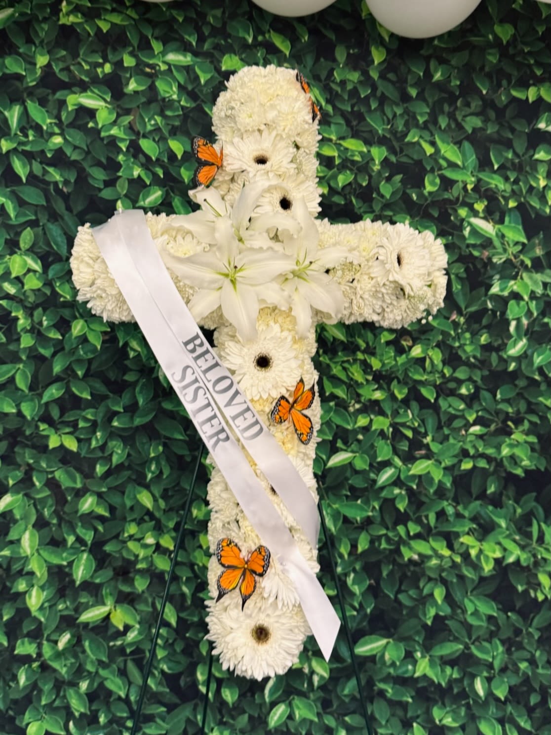 White floral cross with a memorial ribbon and orange butterflies