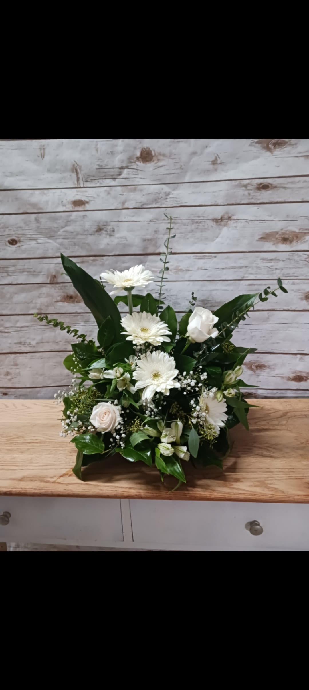 White gerbera daisies and roses in a low green arrangement