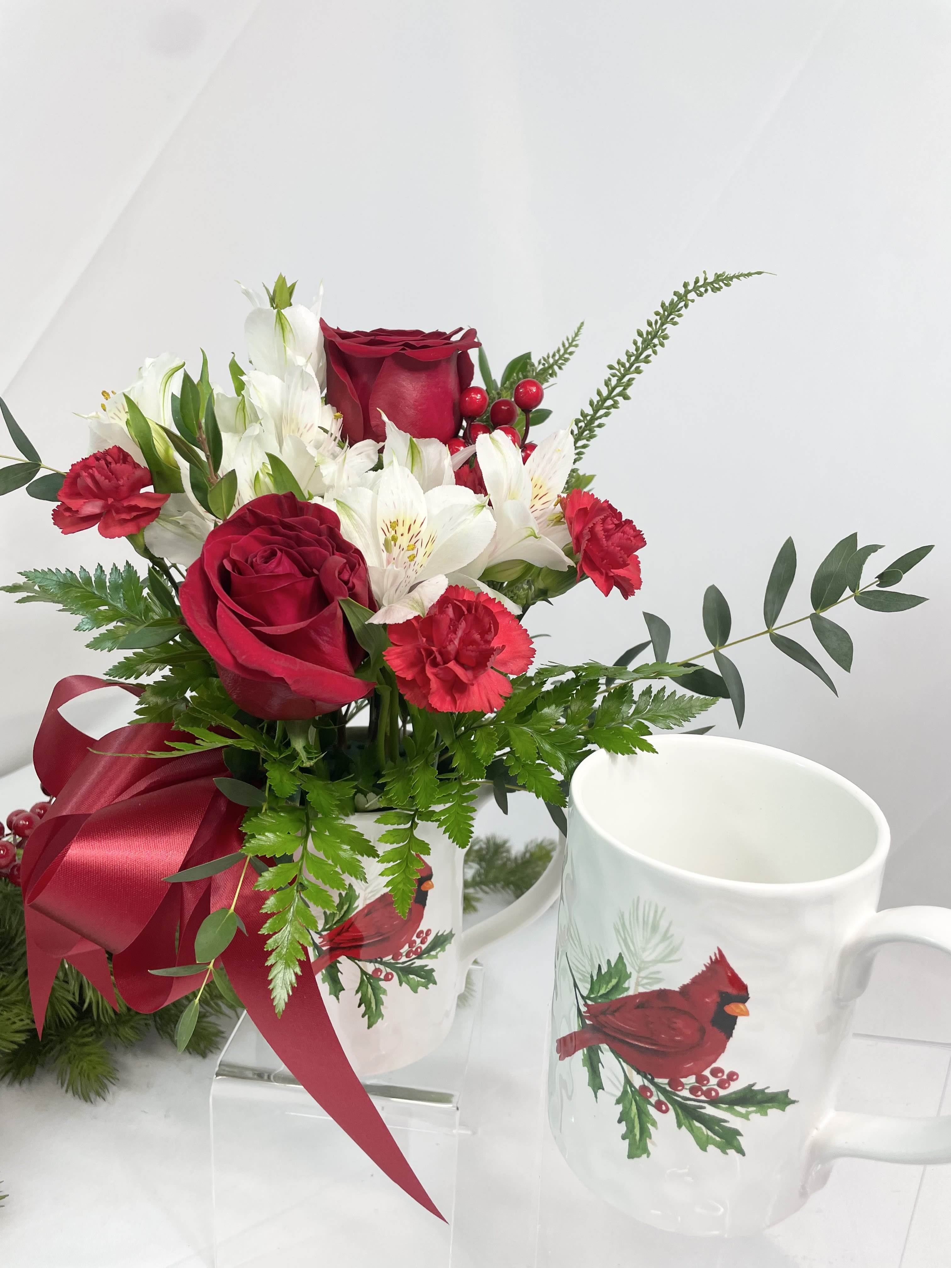 Red roses and white flowers in a mug with a ribbon bow