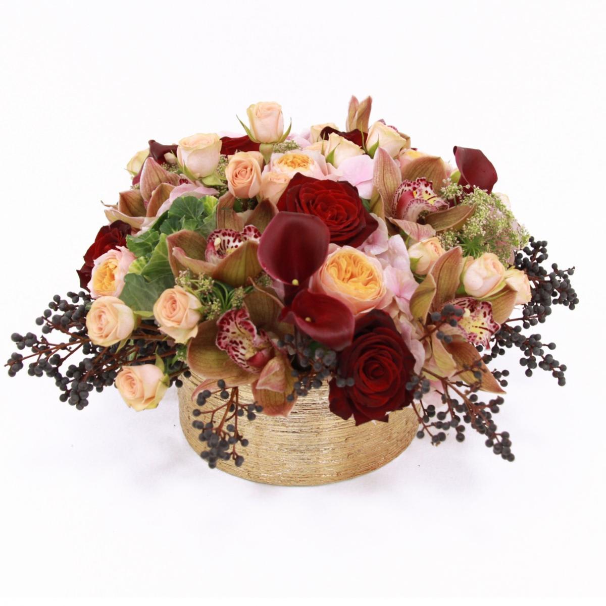 Queen Berry low  Arrangement -  low gold bowl vase filled with lush flowers including red roses, peach garden roses, burgundy mini calla lilies, cymbidium orchids, spray roses, privet berry and queen anne's lace 