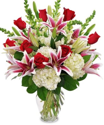 Bouquet of red roses, pink lilies, and white hydrangeas in a glass vase