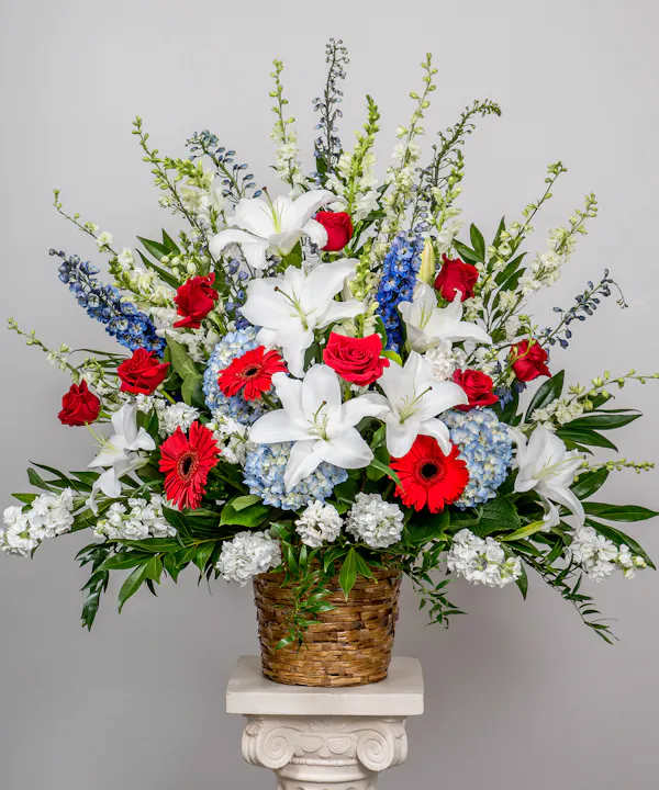 majestic standing basket - The love they showed for their country is as deep as the love felt by those mourning their loss. Meticulously crafted by our expert florists to honor a proud veteran who has passed away, our majestic standing basket arrangement is filled with lush blooms in patriotic red, white and blue, creating a fitting final tribute for the funeral services.