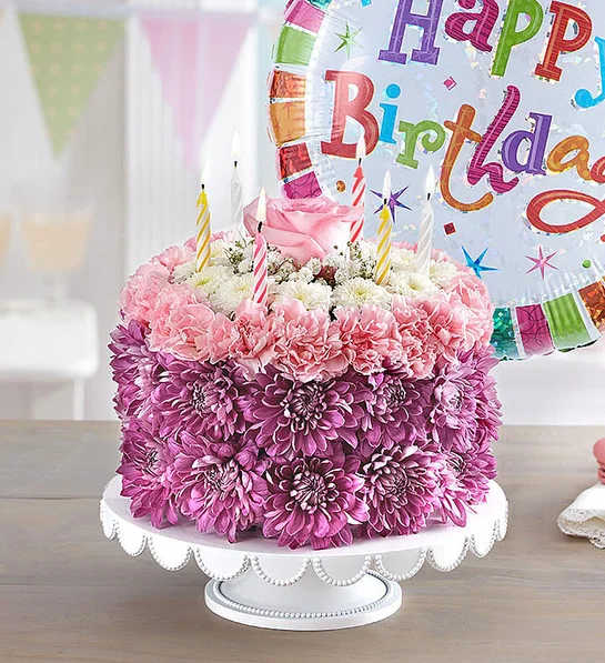 Pink and purple flower cake with birthday candles and a balloon