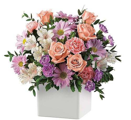 Mixed pink, purple, and white flowers in a white square vase