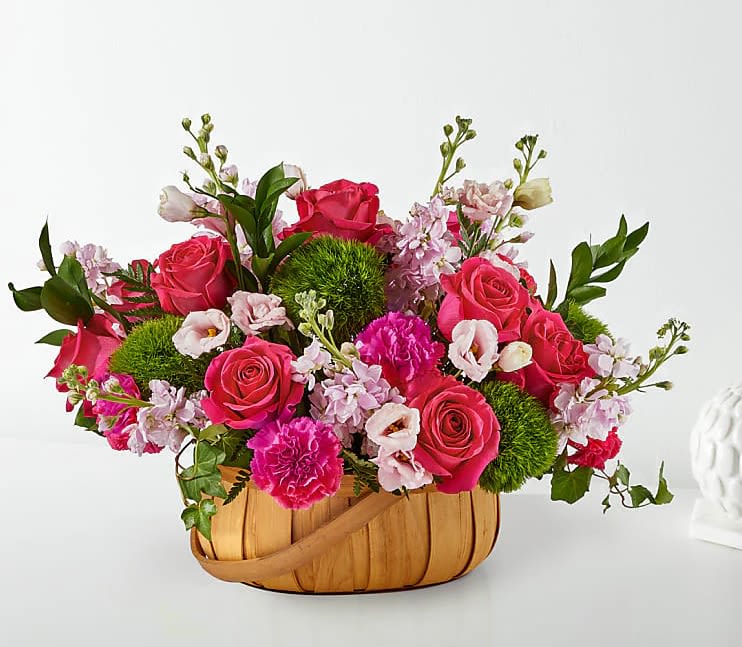 Pink roses and carnations in a woven basket