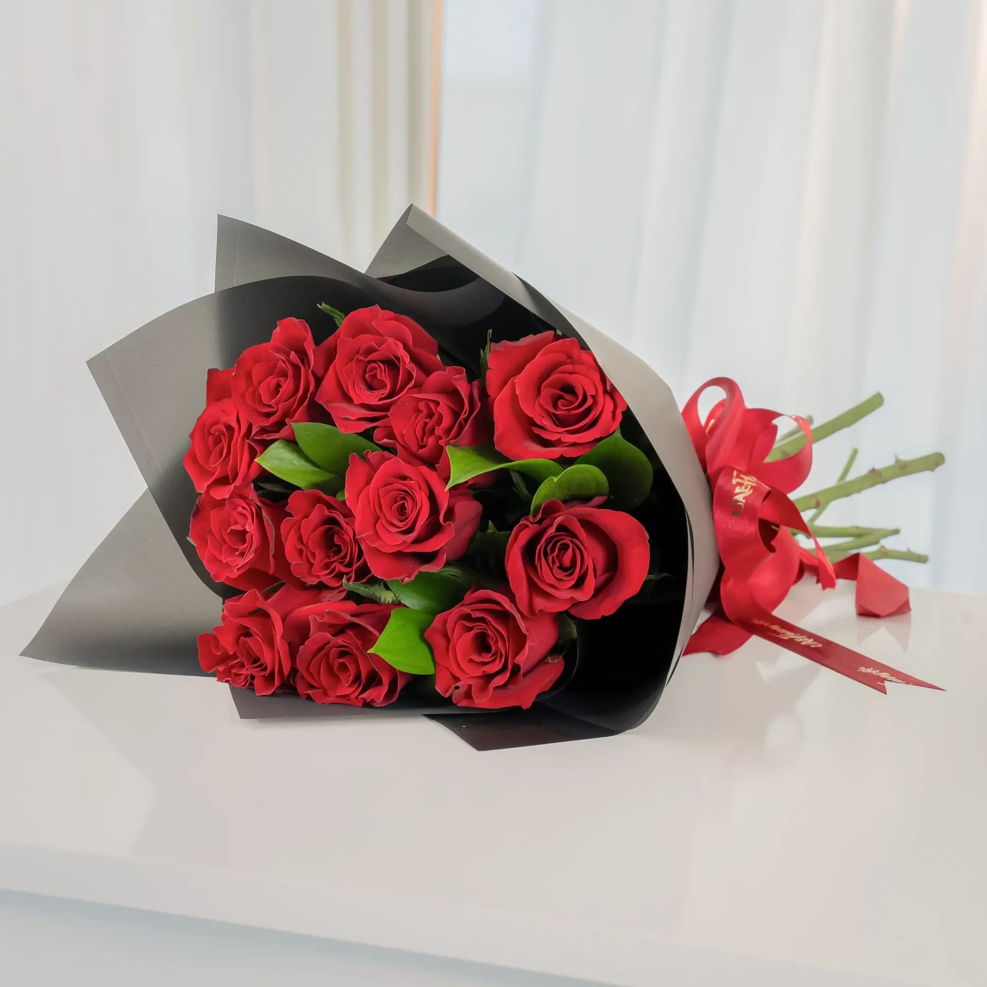 Bouquet of red roses wrapped in black paper with a red ribbon