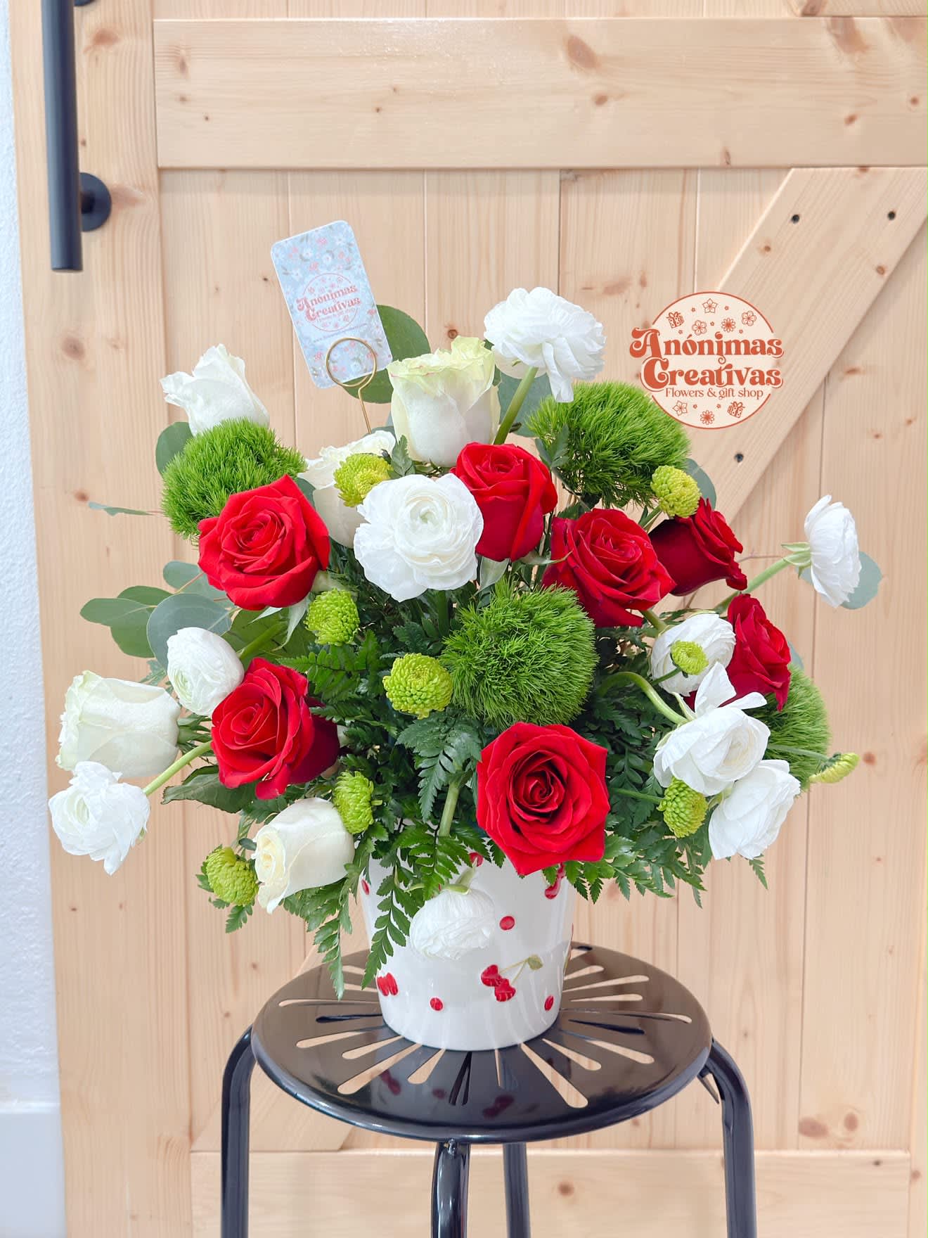 Red and white roses arranged in a white vase with green accents