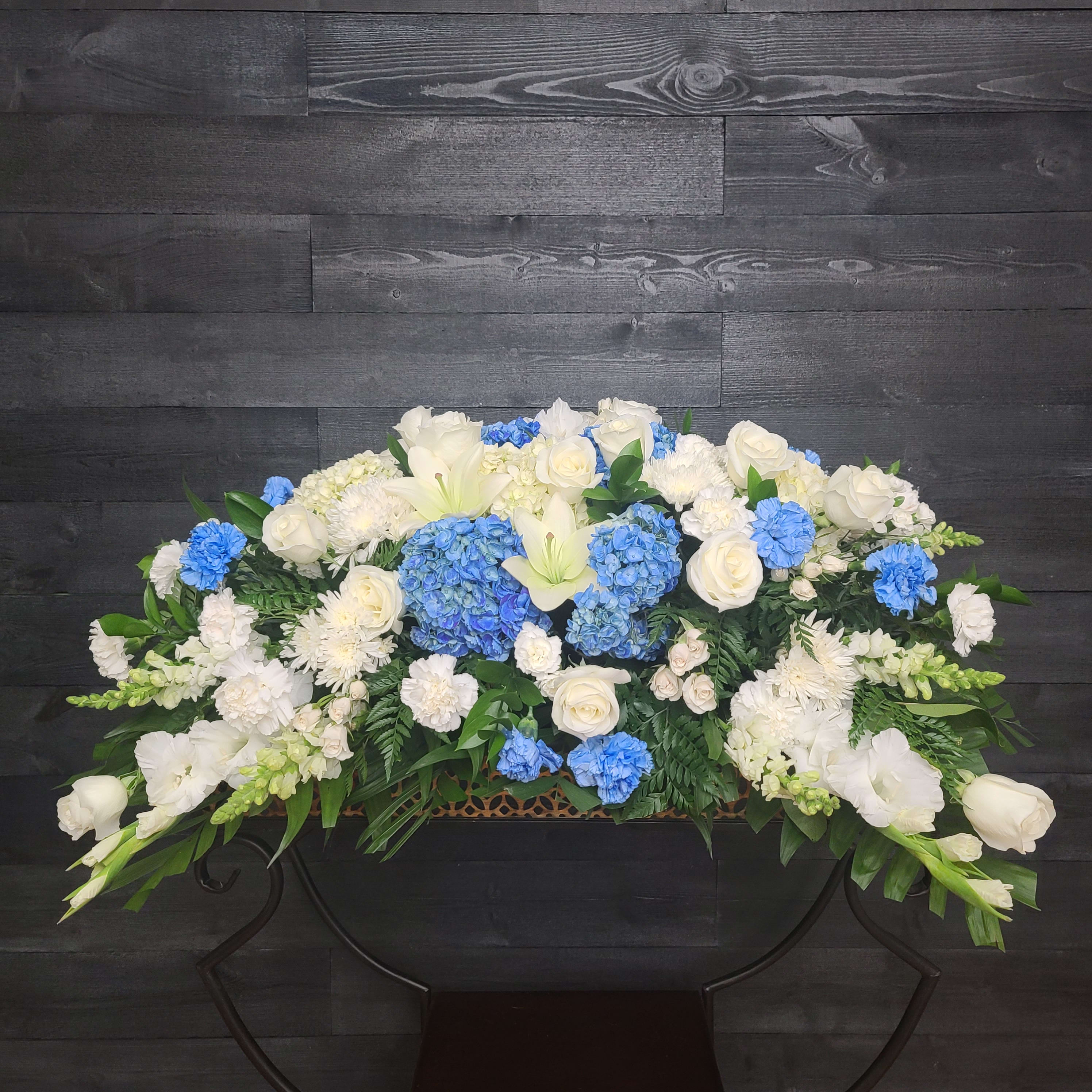 Beyond Blue Casket Spray  - Casket Spray only. Blue delphinium, white lilies and other seasonal blooms. Approximately 34" in length. Last photo represents a matching set. You save 10% when purchasing the set. 