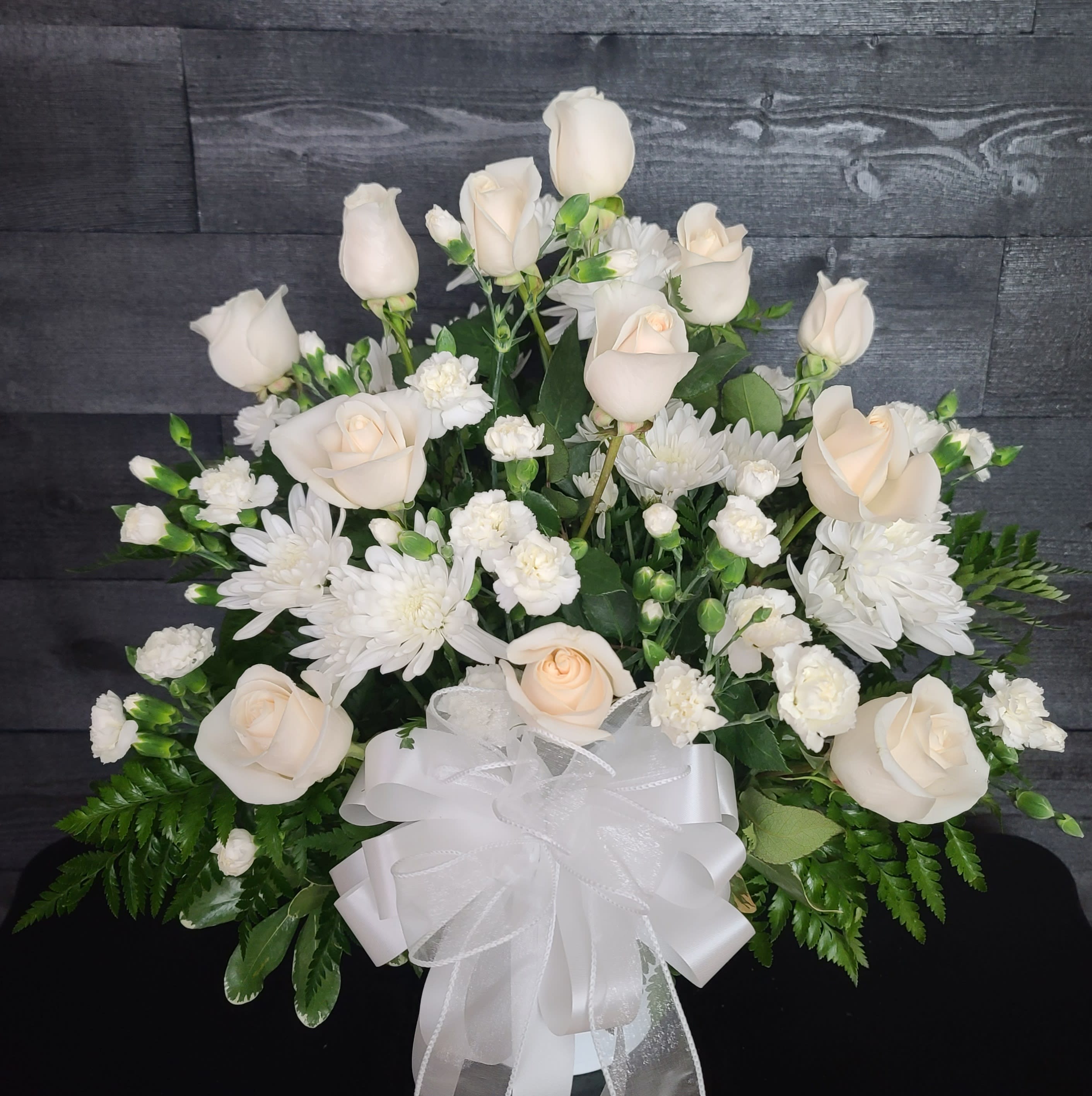 White roses and chrysanthemums arranged with a white ribbon bow