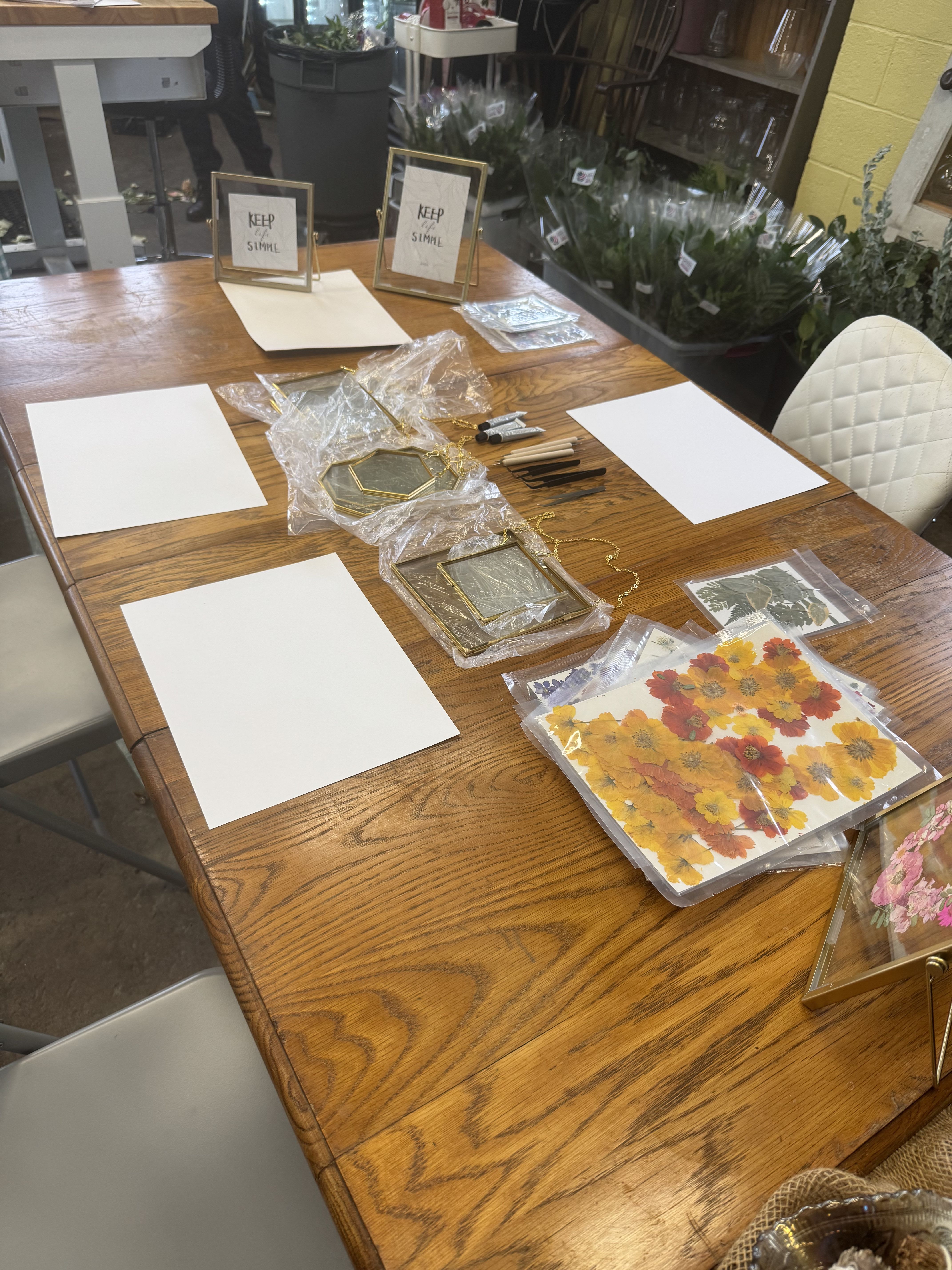 Craft supplies and framed floral pieces arranged on a wooden table