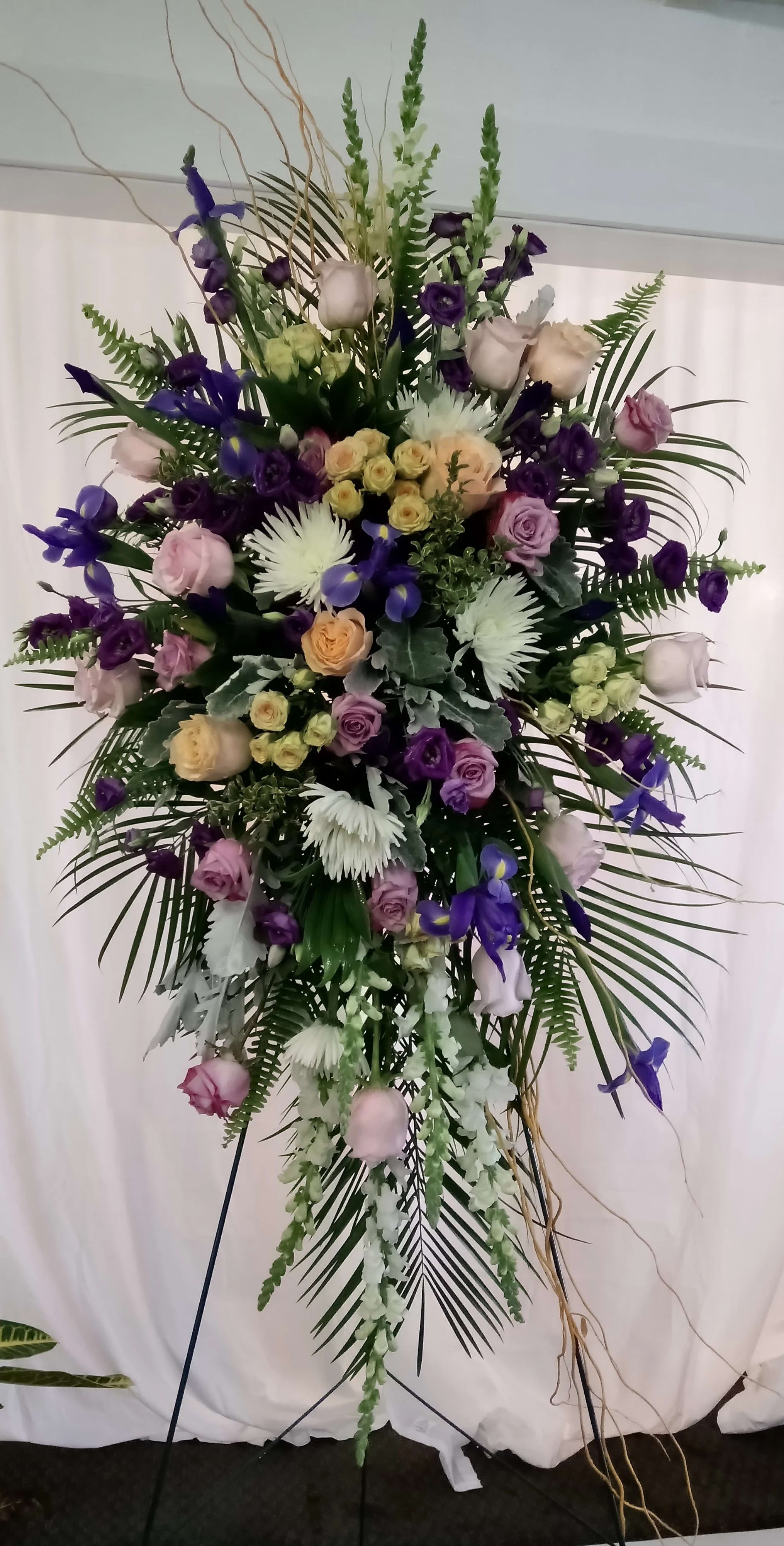 Tall floral standing spray with purple, white, and blush blooms