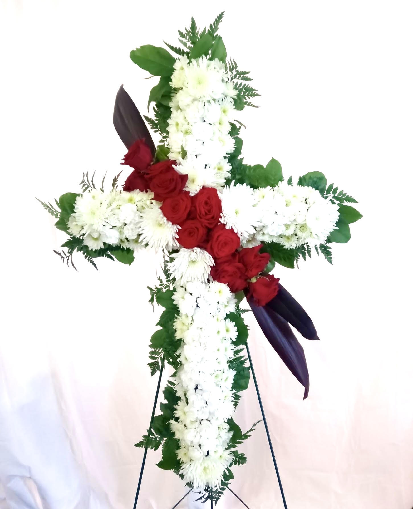Cross-shaped floral tribute with red roses and white chrysanthemums