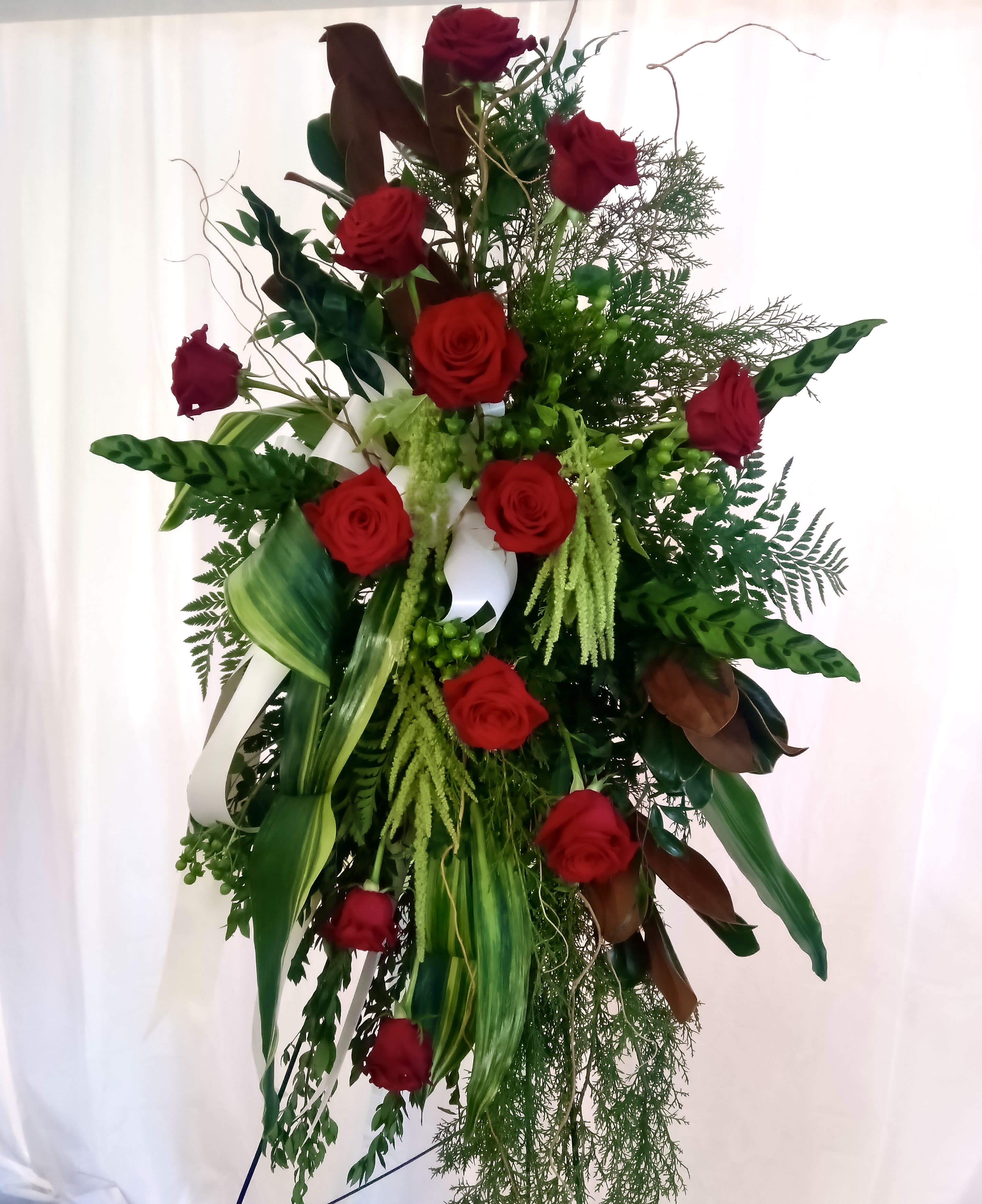 Tall standing arrangement of red roses and mixed greenery