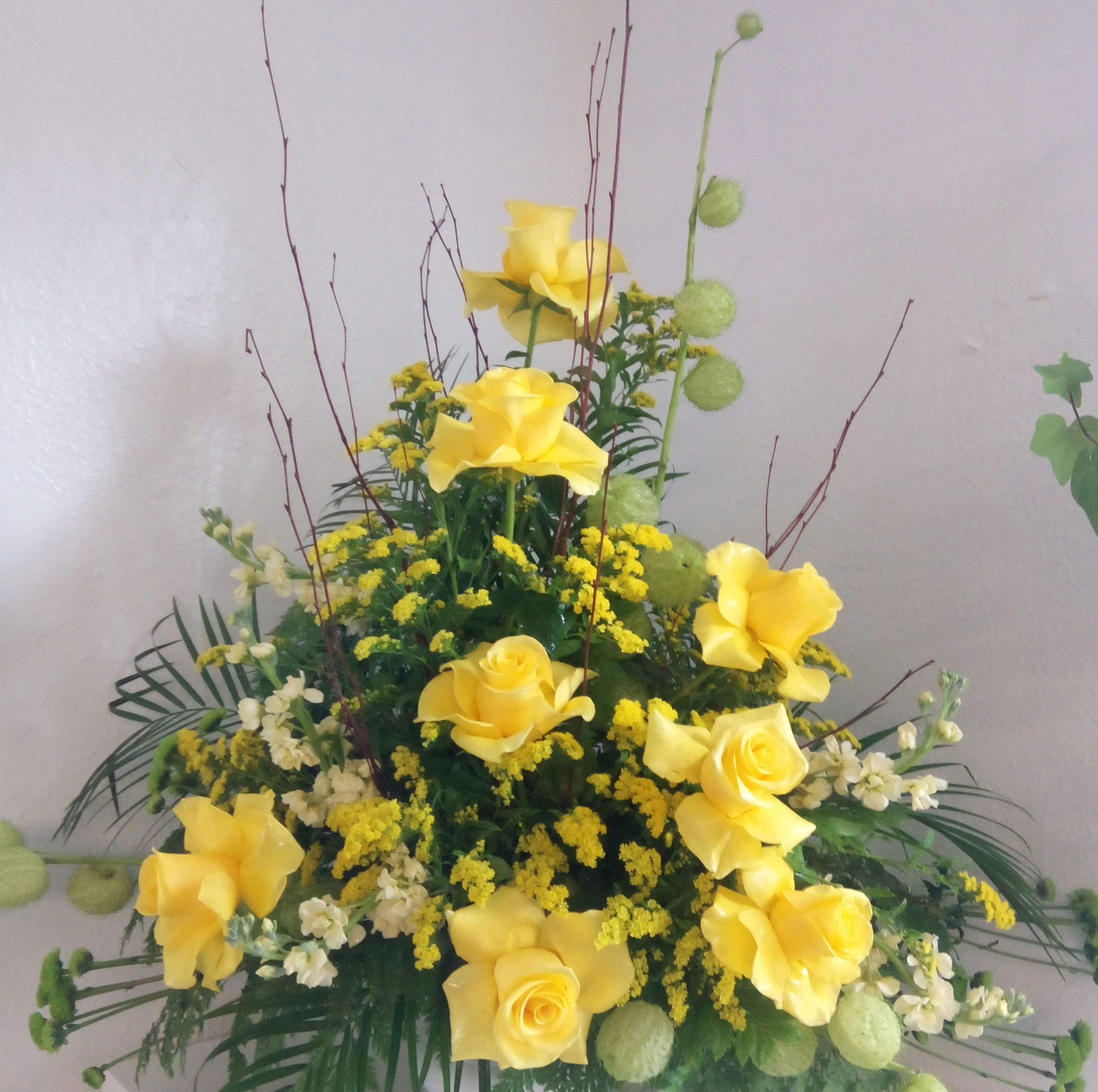 Tall arrangement of yellow roses with white flowers and green accents
