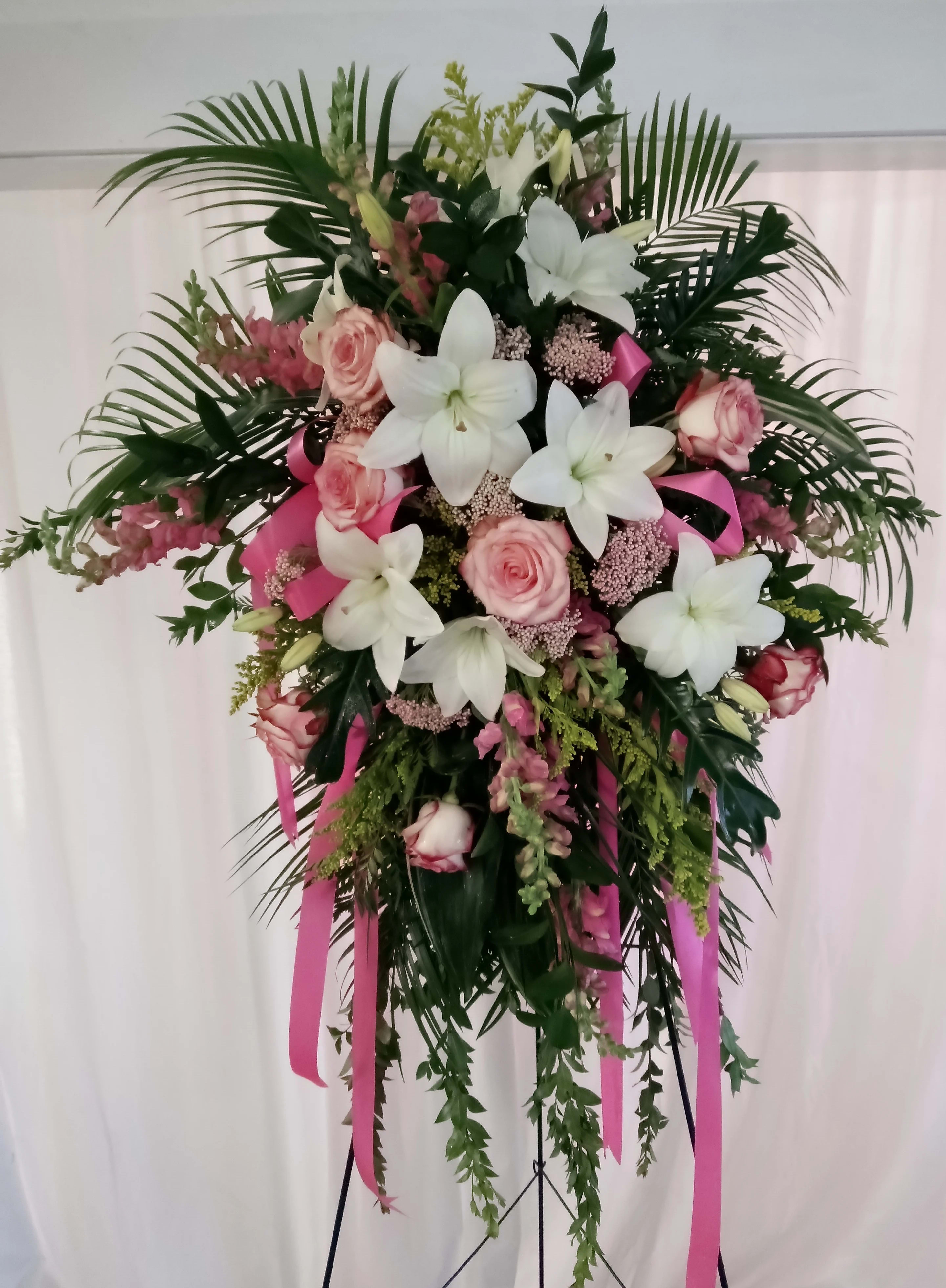 Standing floral spray with white lilies and pink roses on a pink ribboned easel