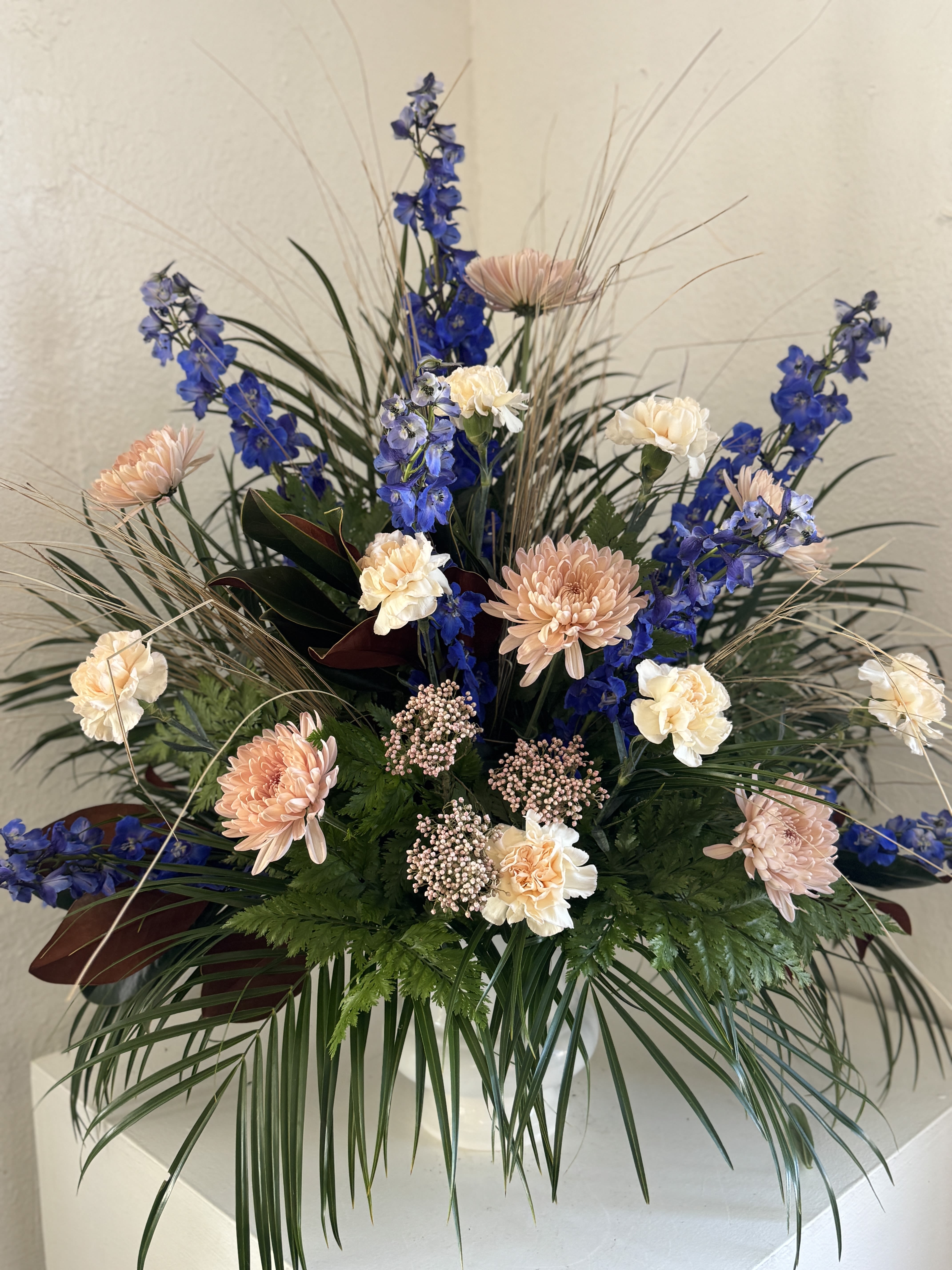 Tall floral arrangement with blue and peach blooms in a vase