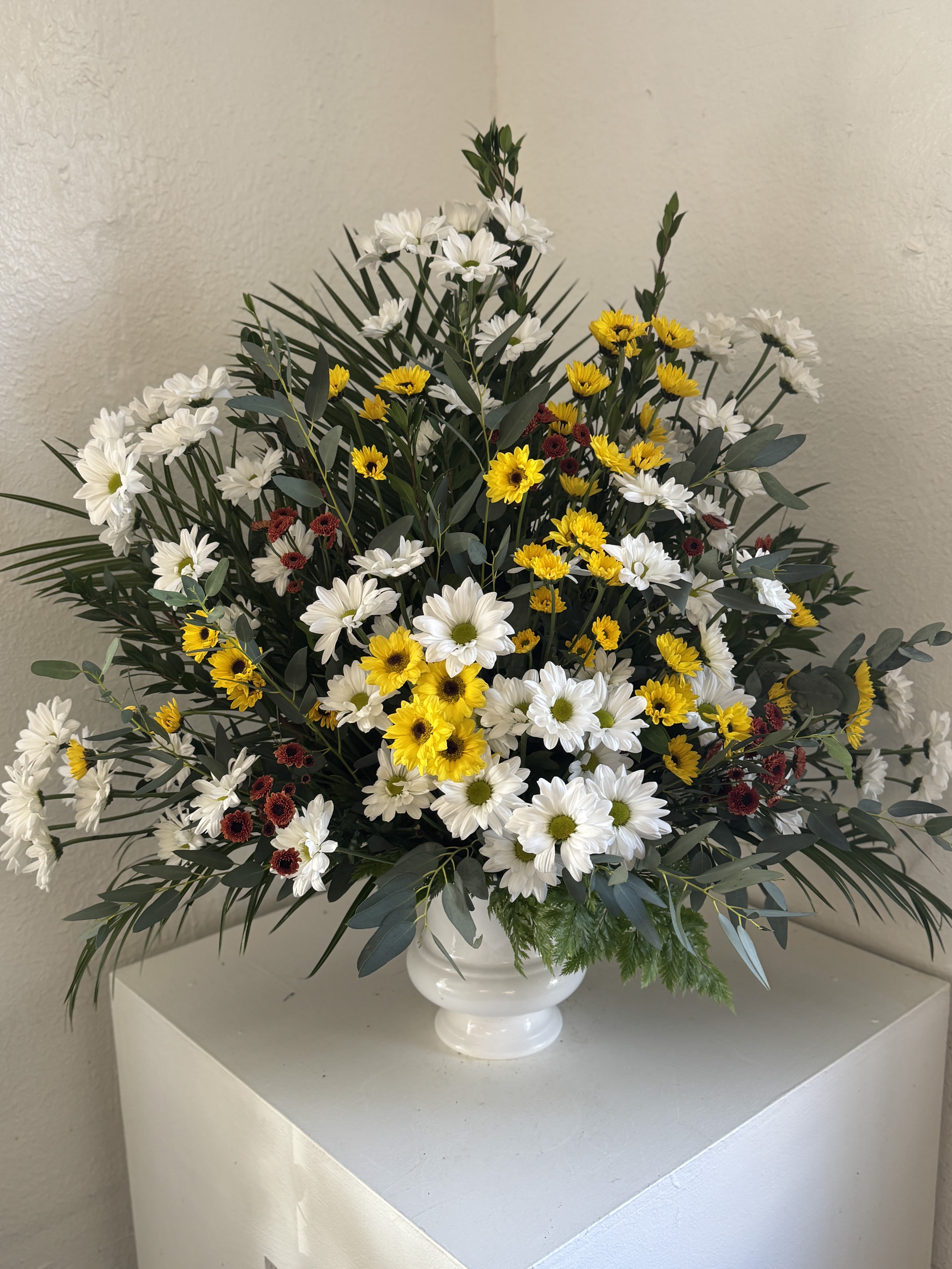 White and yellow daisy arrangement in a white vase