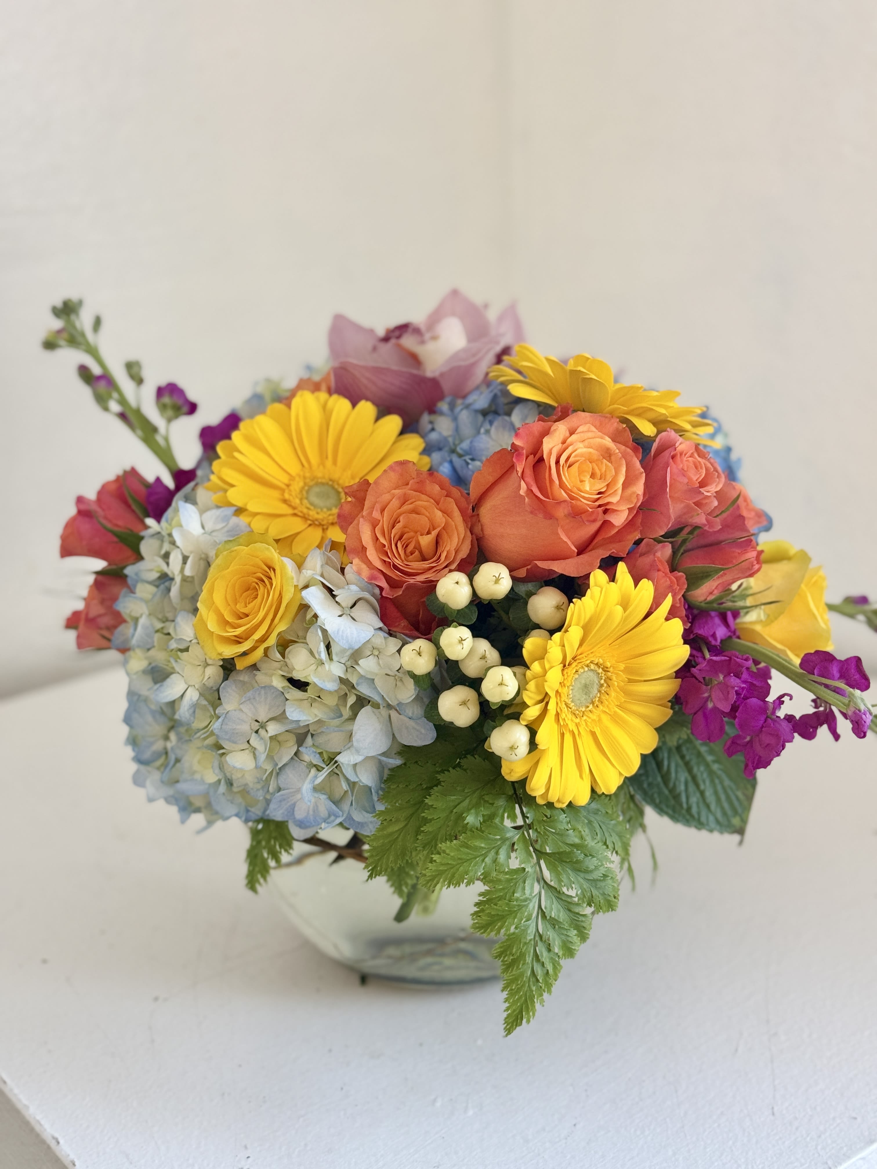 Colorful bouquet with roses, hydrangea, and yellow daisies in a vase