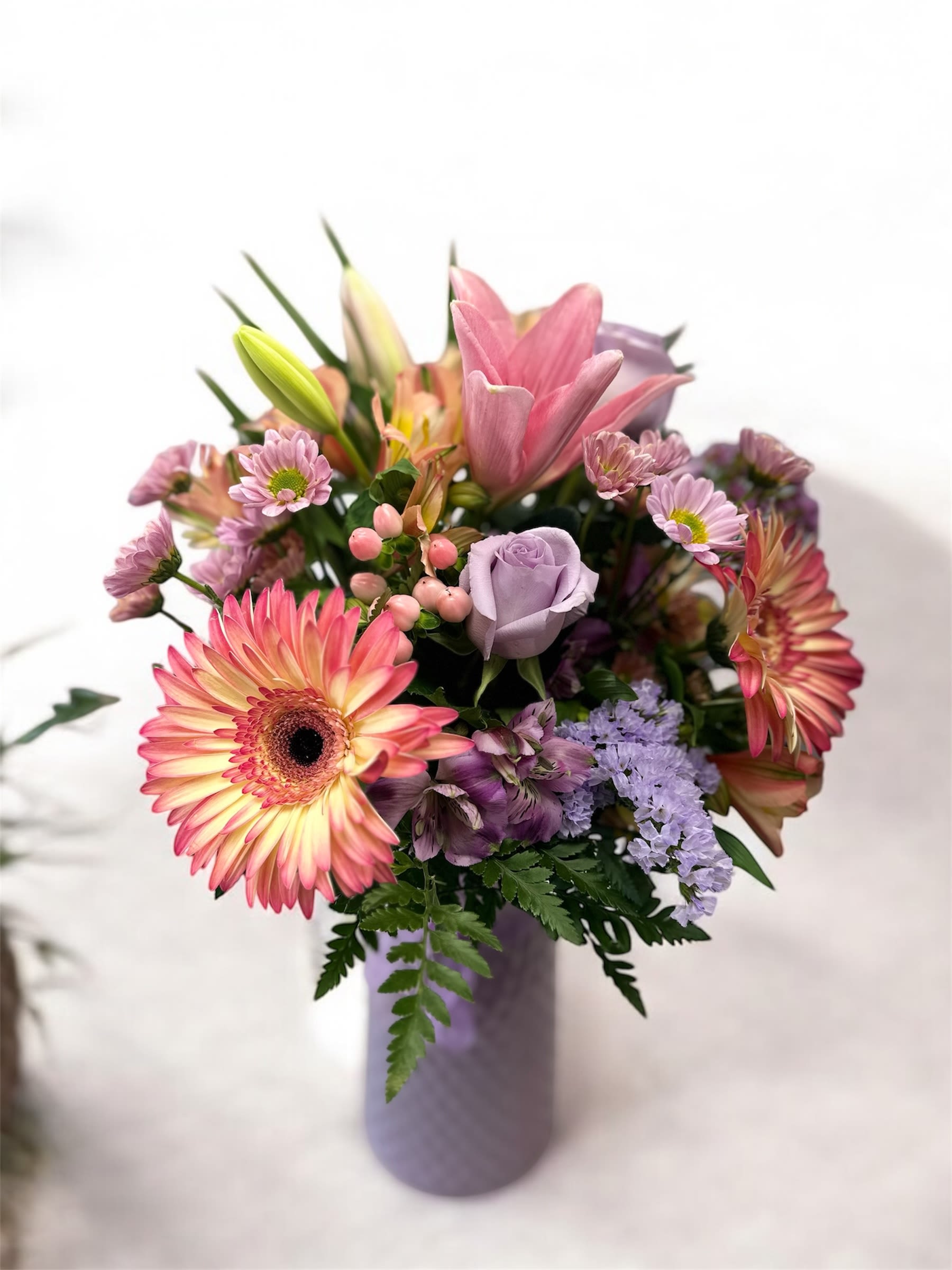 Mixed bouquet in a lavender vase with pink and purple flowers