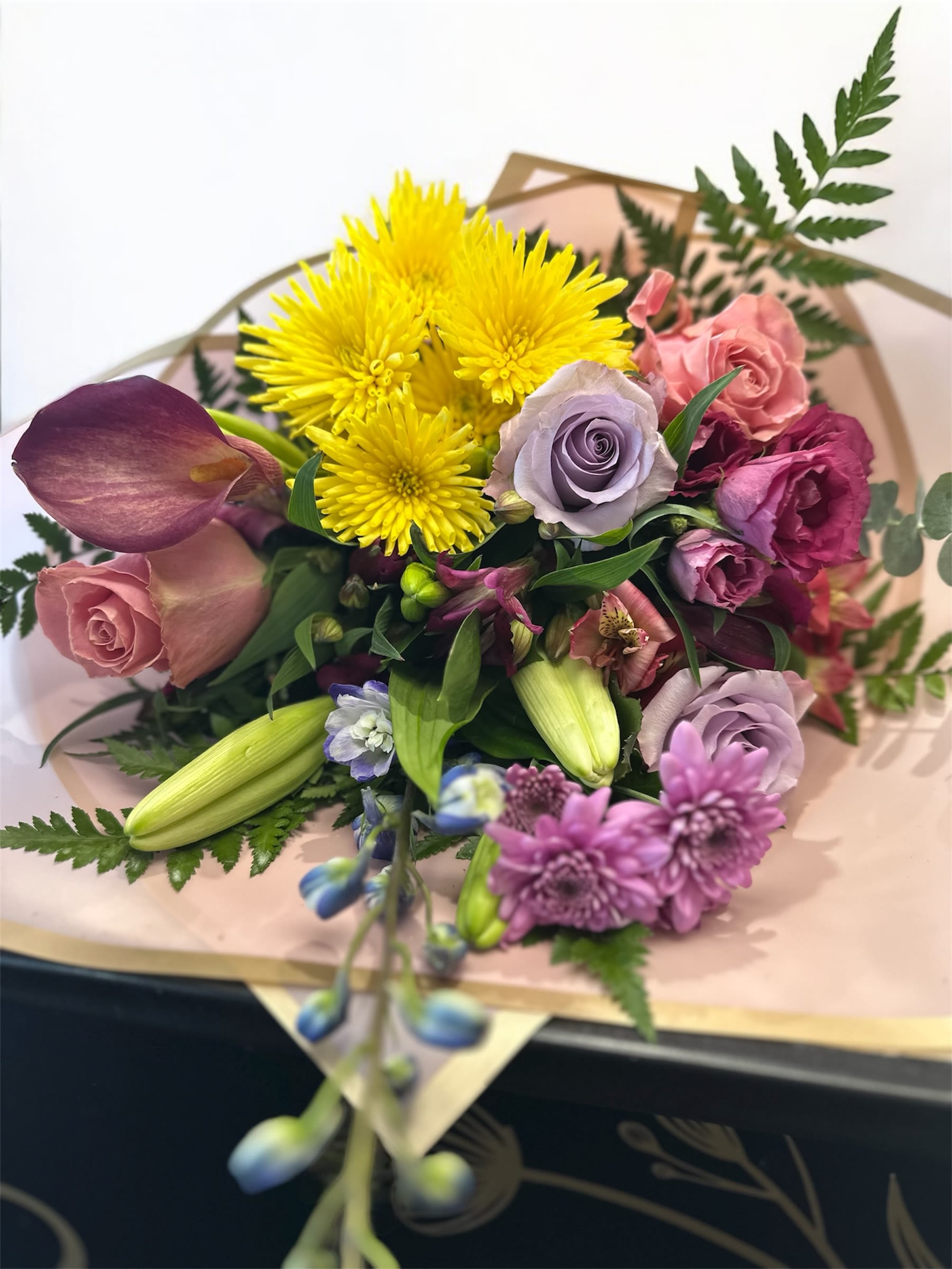 Mixed bouquet with yellow chrysanthemums, roses, and lilies wrapped in paper