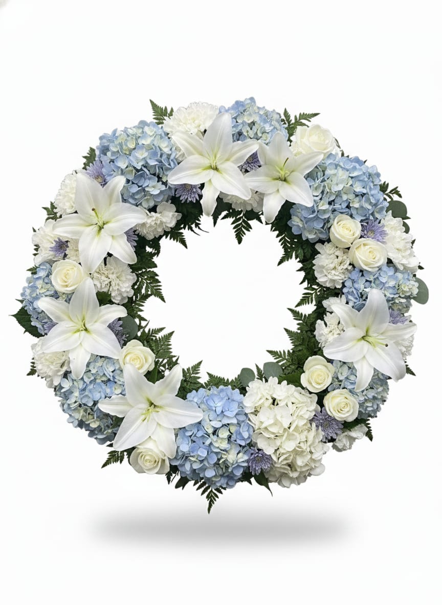 Circular wreath of white lilies, blue hydrangeas, and white roses