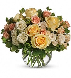 Bouquet of cream, peach, and yellow roses in a clear glass vase