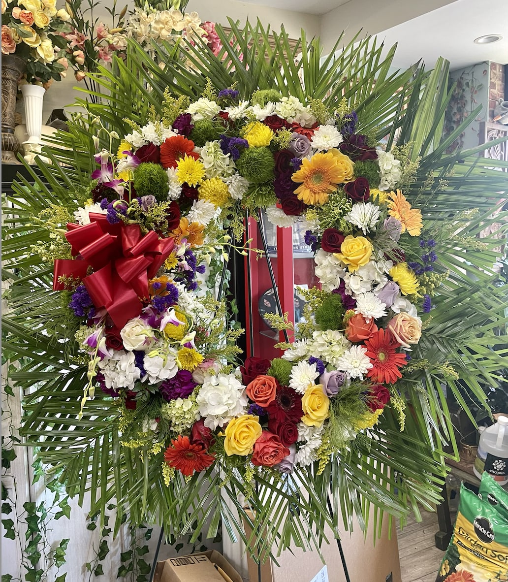 Open Wreath (Deluxe Shown) - This colorful and bright wreath spray is representative of a life lived to its fullest. Colors and Flowers may change based off of season and availability.