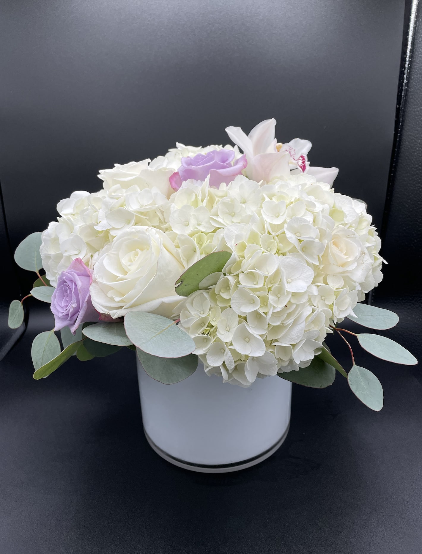 White hydrangea and roses in a white vase with pale purple accents