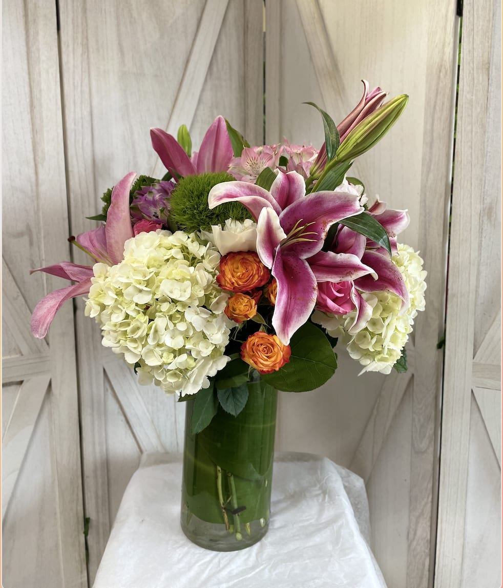 Pink lilies and white hydrangeas in a tall glass vase