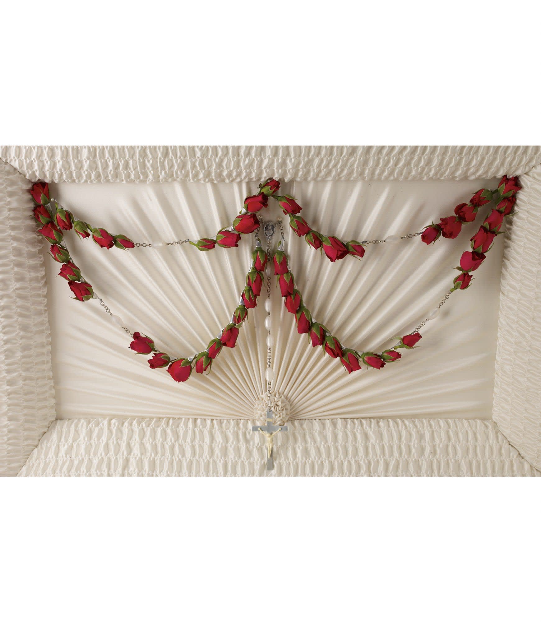 White casket with red rose garland and a rosary cross