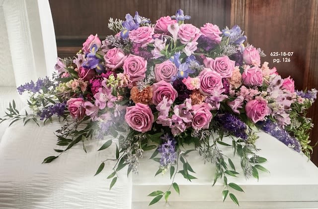 Large pink and purple floral casket spray with roses and lilies