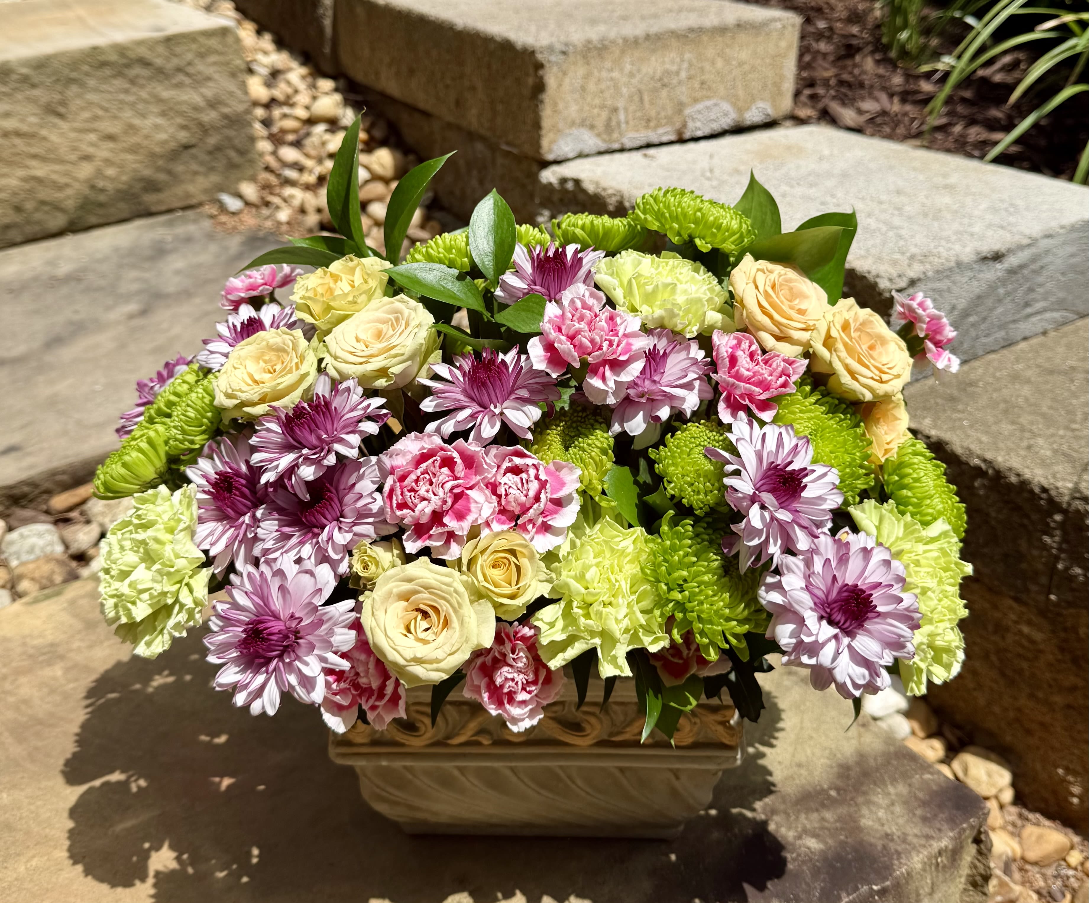 Garden Whimsey - A lush blend of roses, carnations, and daisies in soft pastels and fresh greens, creating a romantic, garden-inspired centerpiece.