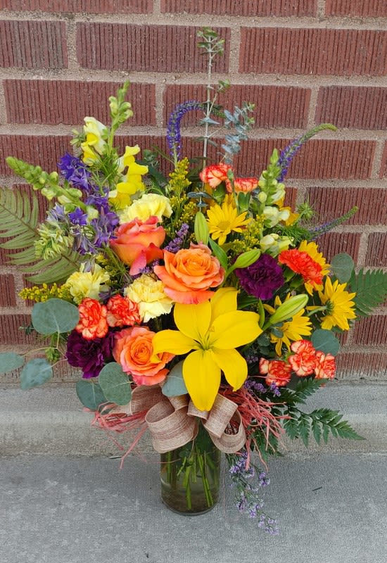 Colorful mixed bouquet in a glass vase with roses and lilies