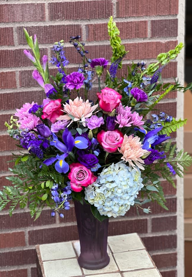 Colorful bouquet in a tall dark vase with roses, hydrangea, and purple blooms