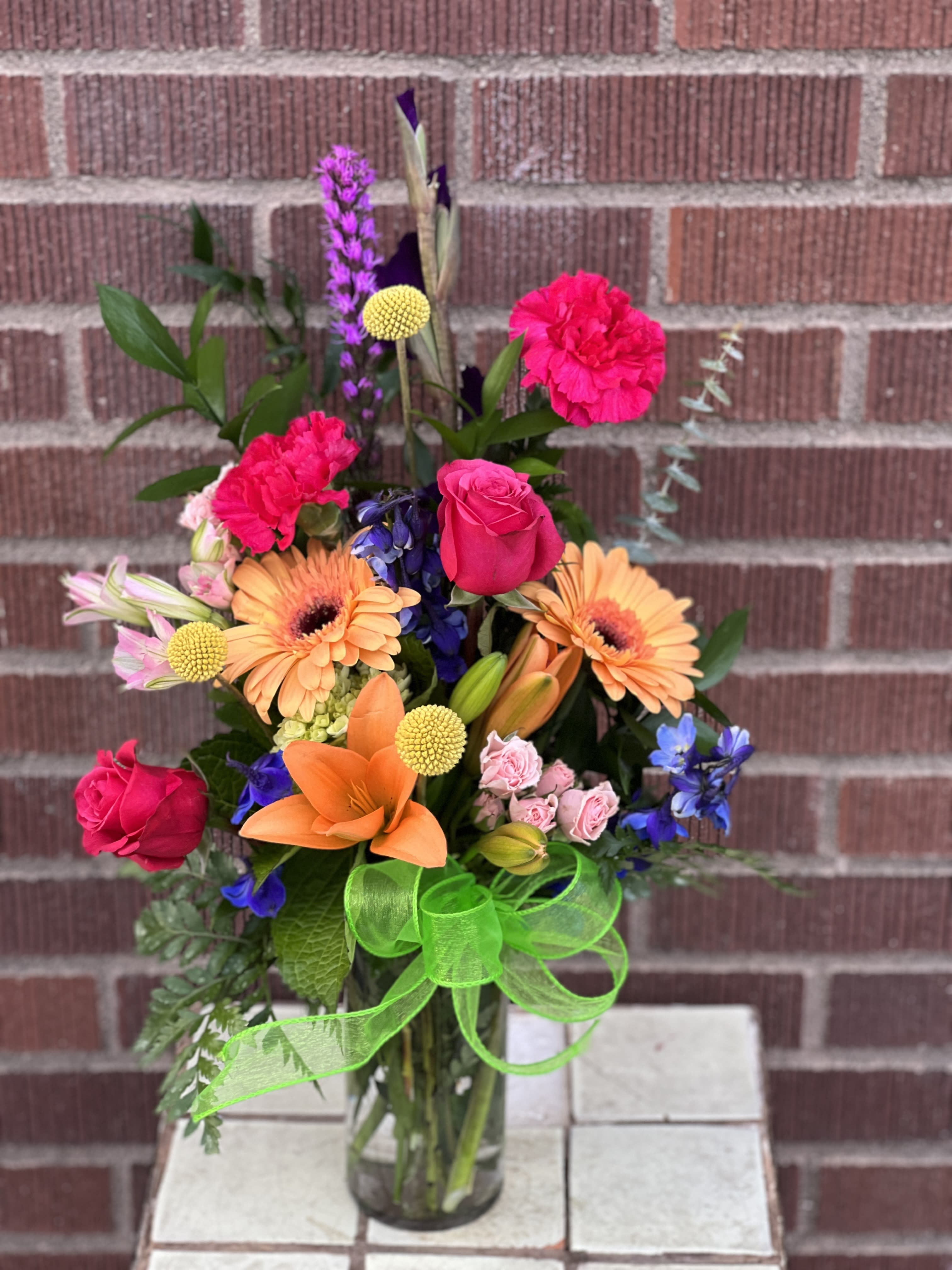 Mixed bouquet in a glass vase with bright pink, orange, purple, and blue flowers
