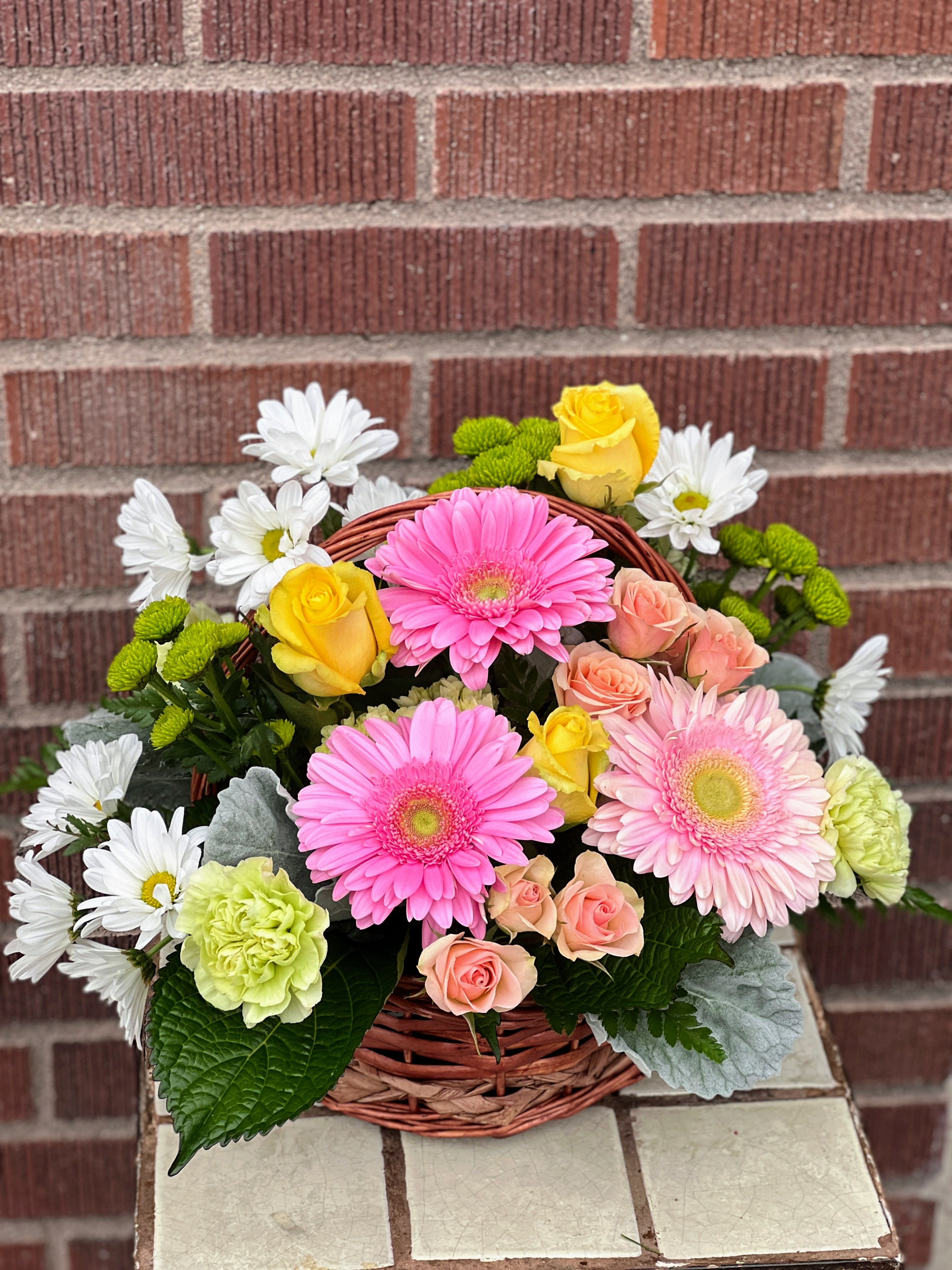 Basket arrangement with pink gerbera daisies, roses, and white daisies