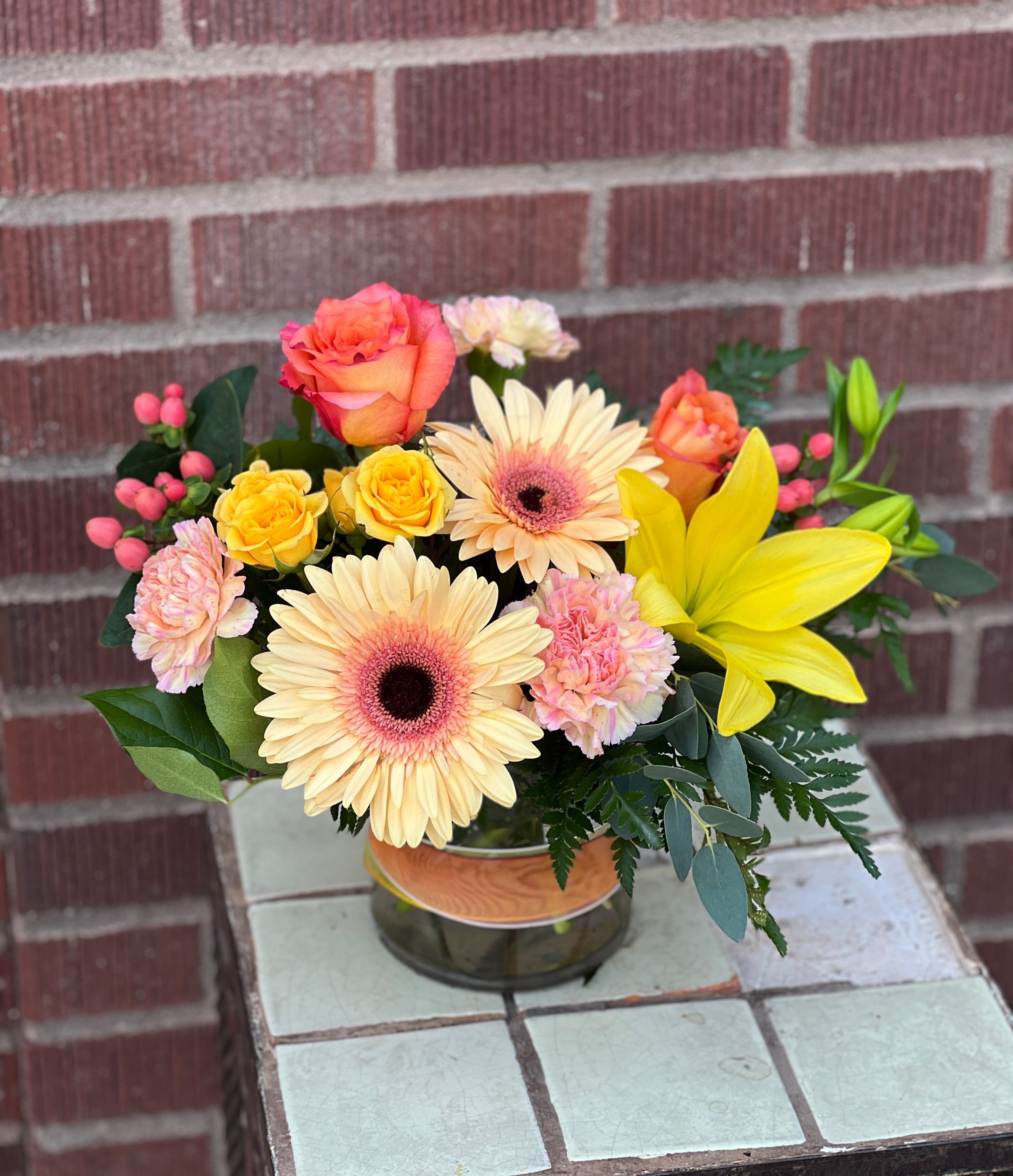 Mixed bouquet in a glass vase with roses, gerbera daisies, lilies, and carnations