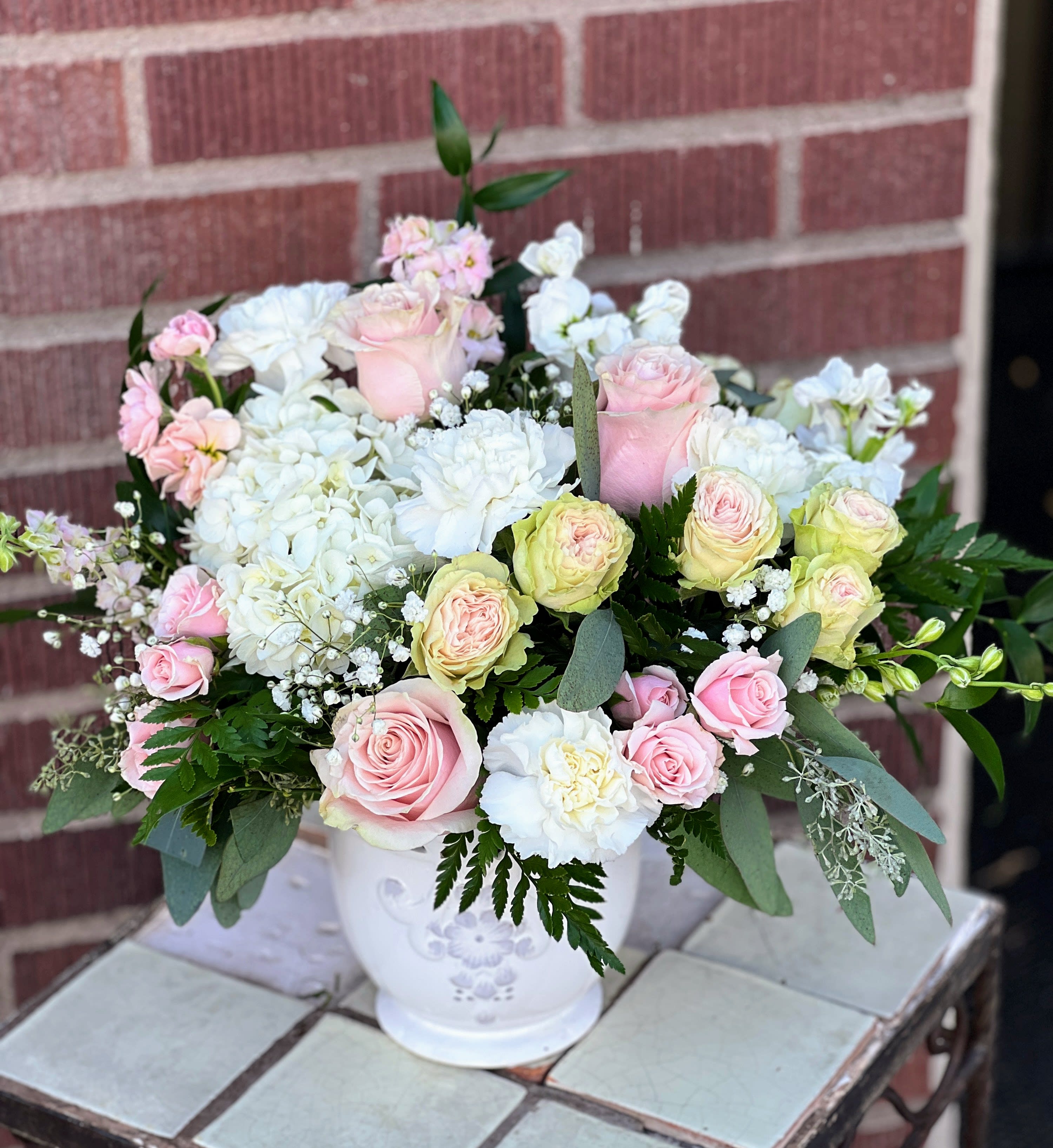 Pink and white rose bouquet in a white ceramic vase