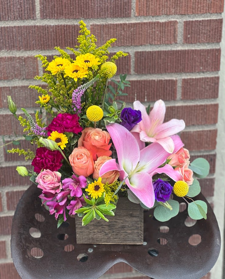 Mixed bouquet with pink lilies, roses, and yellow daisies in a wooden box